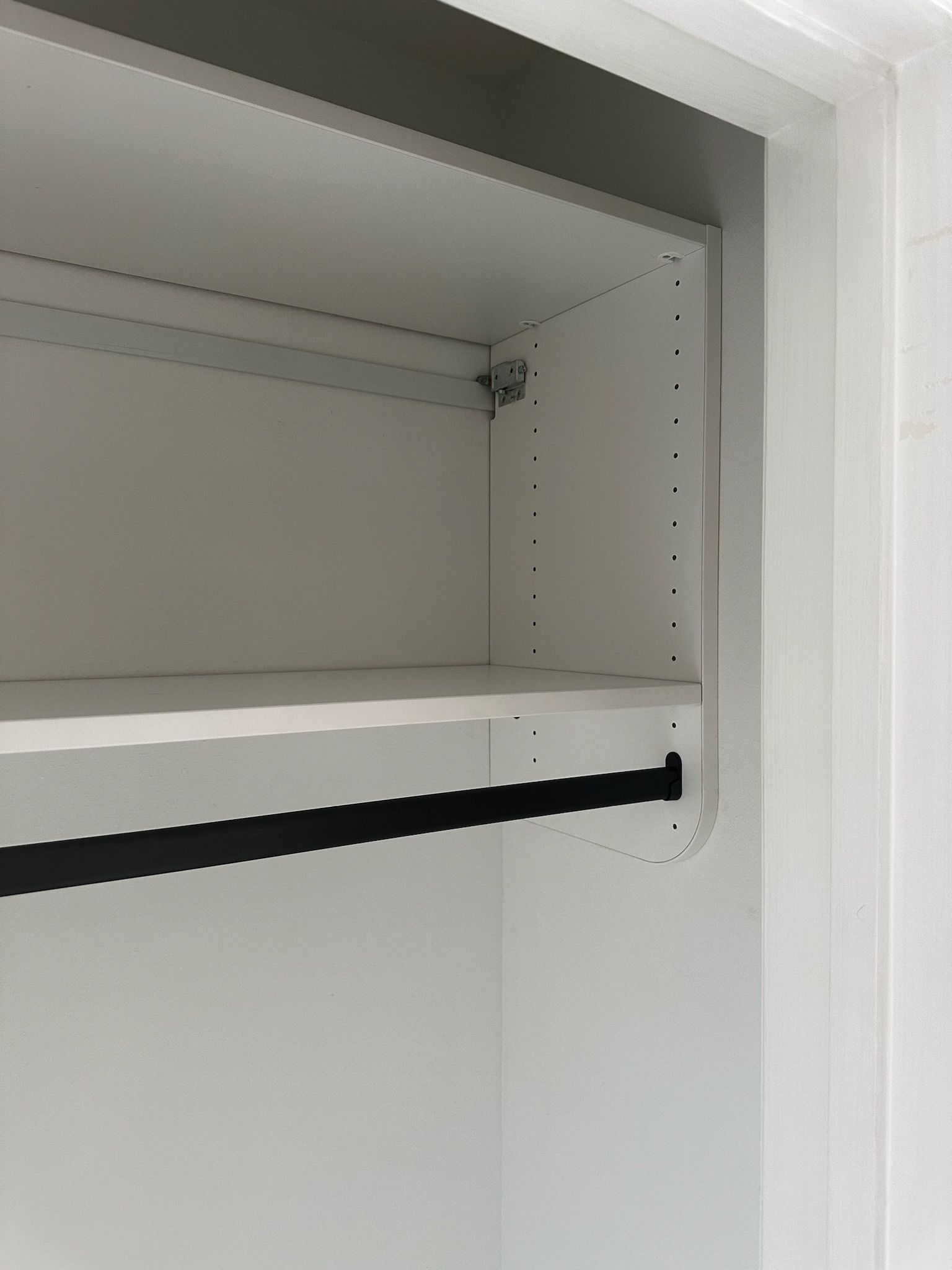 White closet interior with shelf and hanging rod.