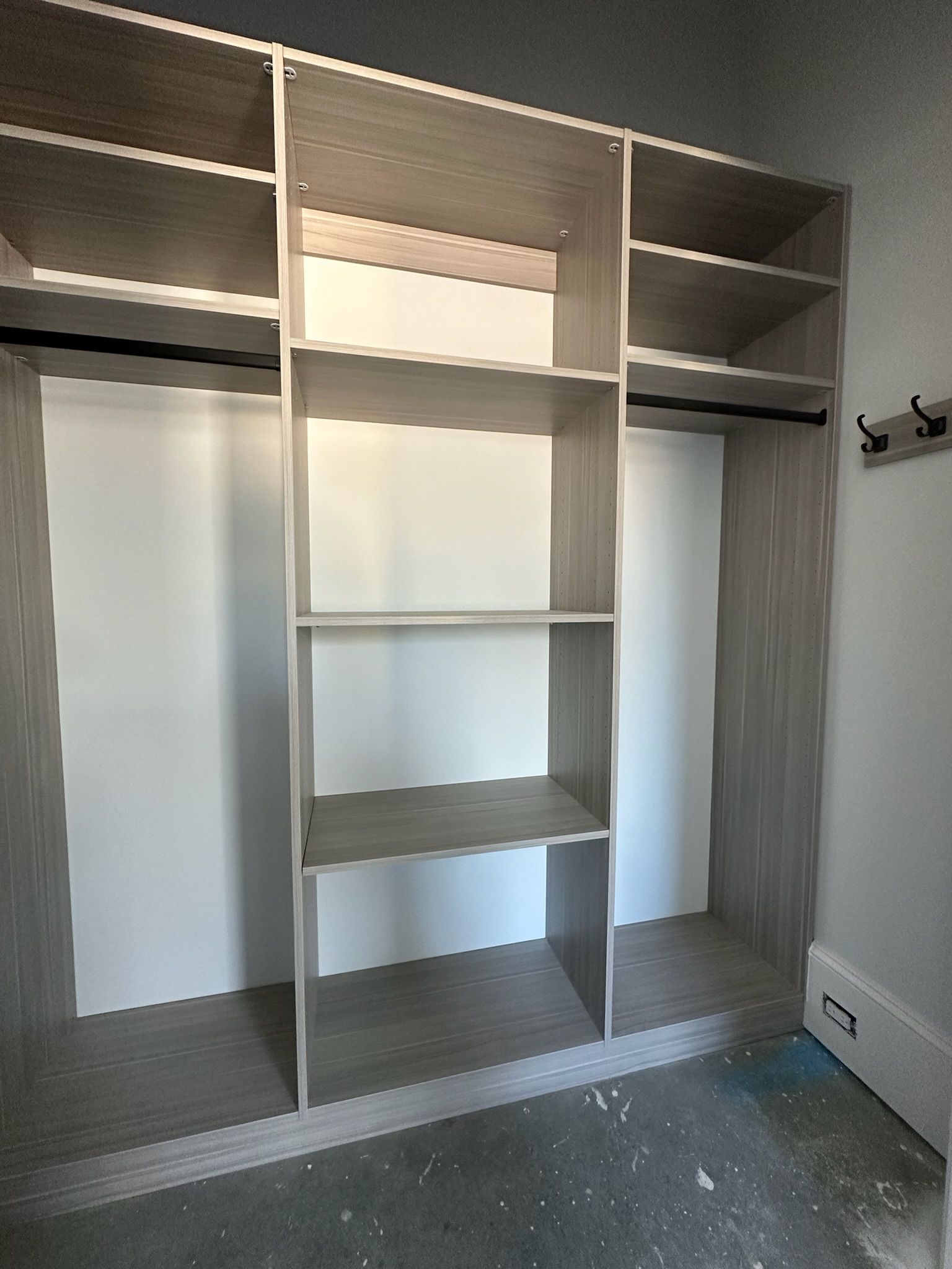 Built-in closet organizer with shelves and hanging rods; light wood finish on white walls.