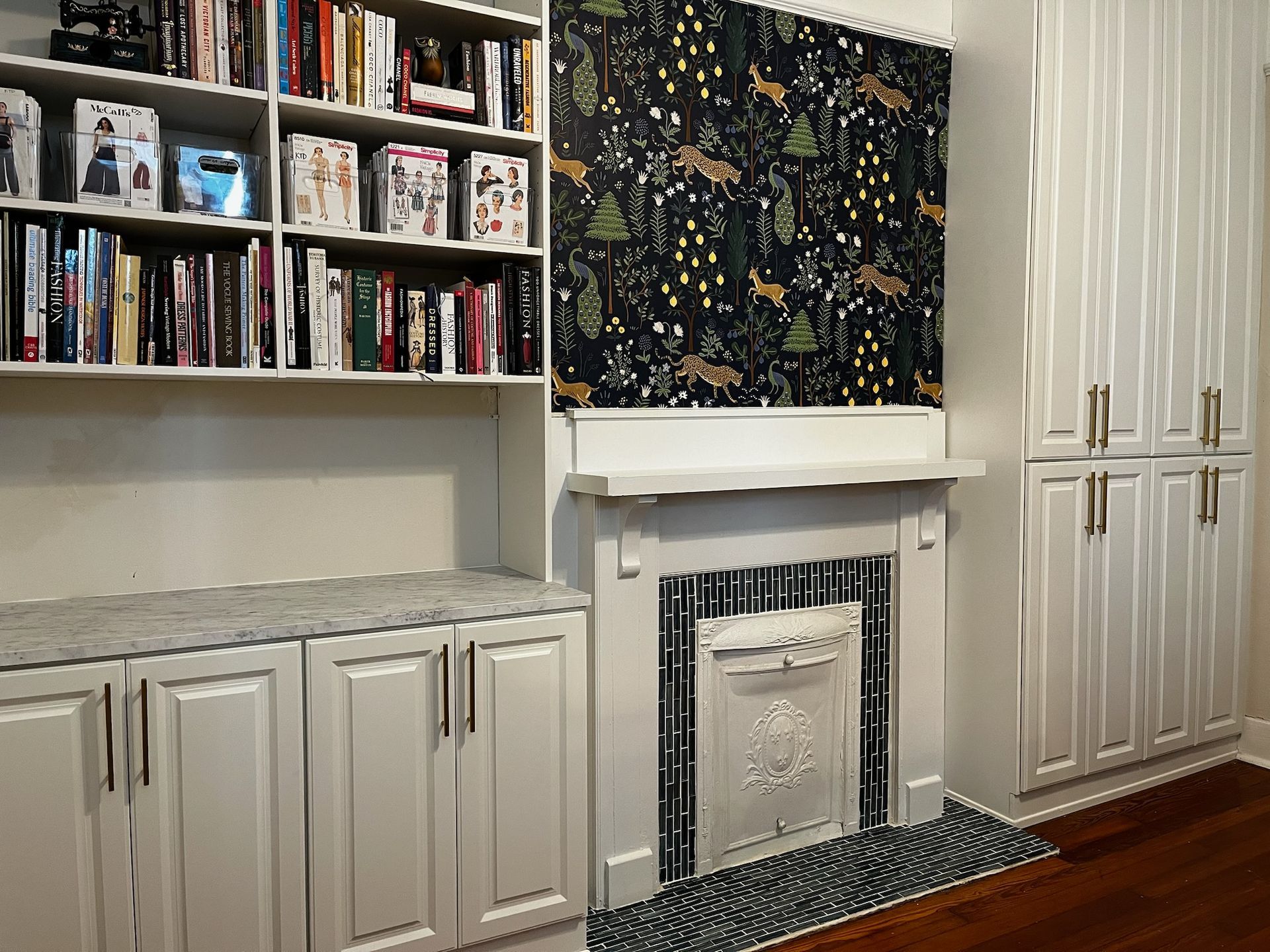 Built-in white bookshelves, cabinets, and a fireplace with decorative wallpaper.