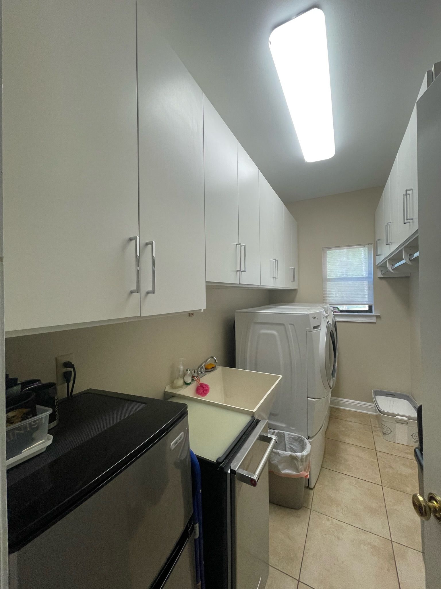 Laundry room with white cabinets, washer, dryer, and utility sink.