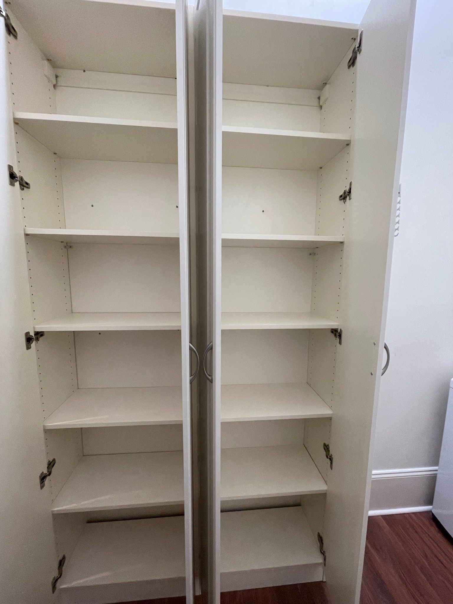 Empty white shelving unit with open doors.