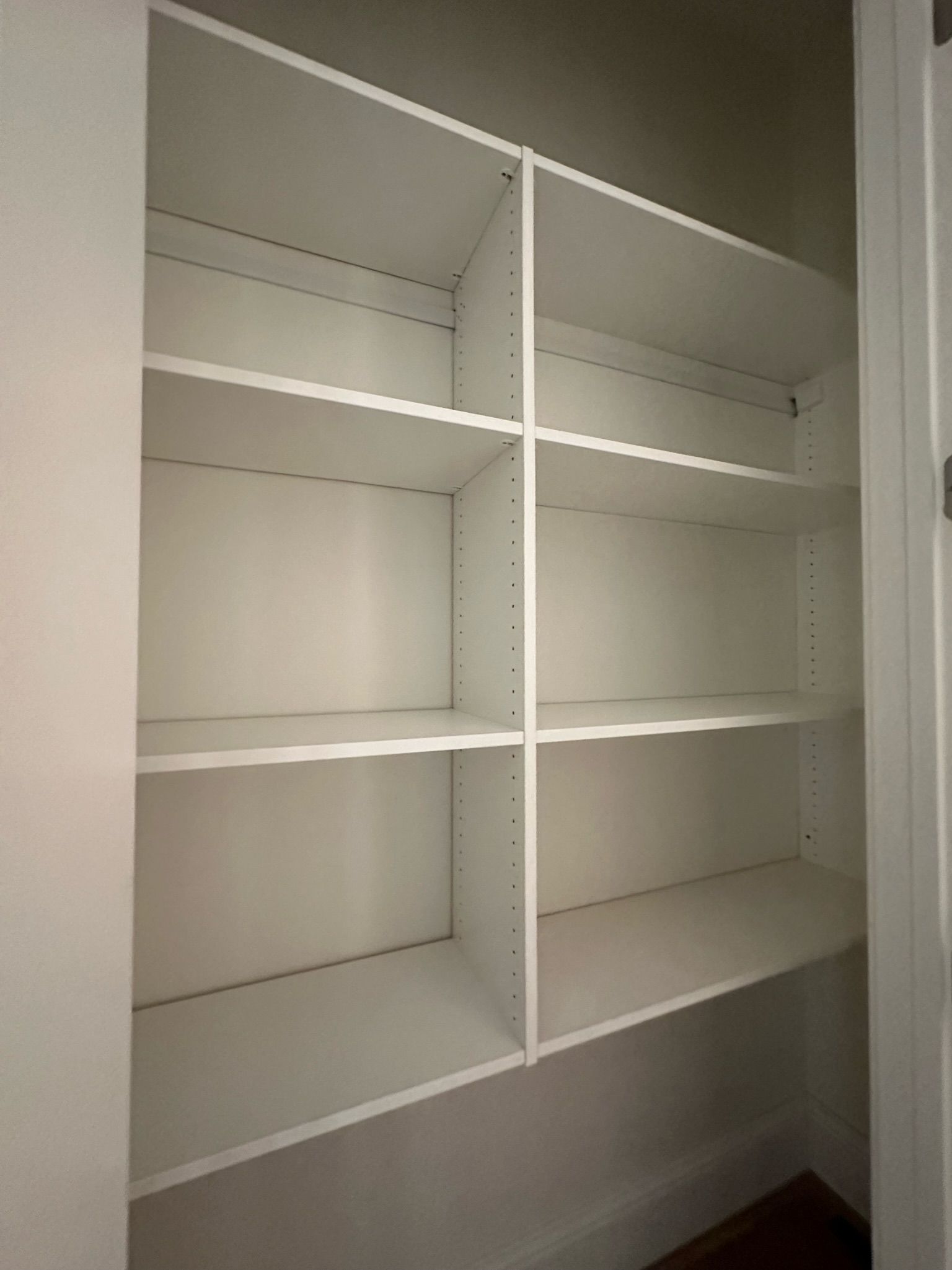 White built-in closet with adjustable shelves, vertical dividers, and empty space.