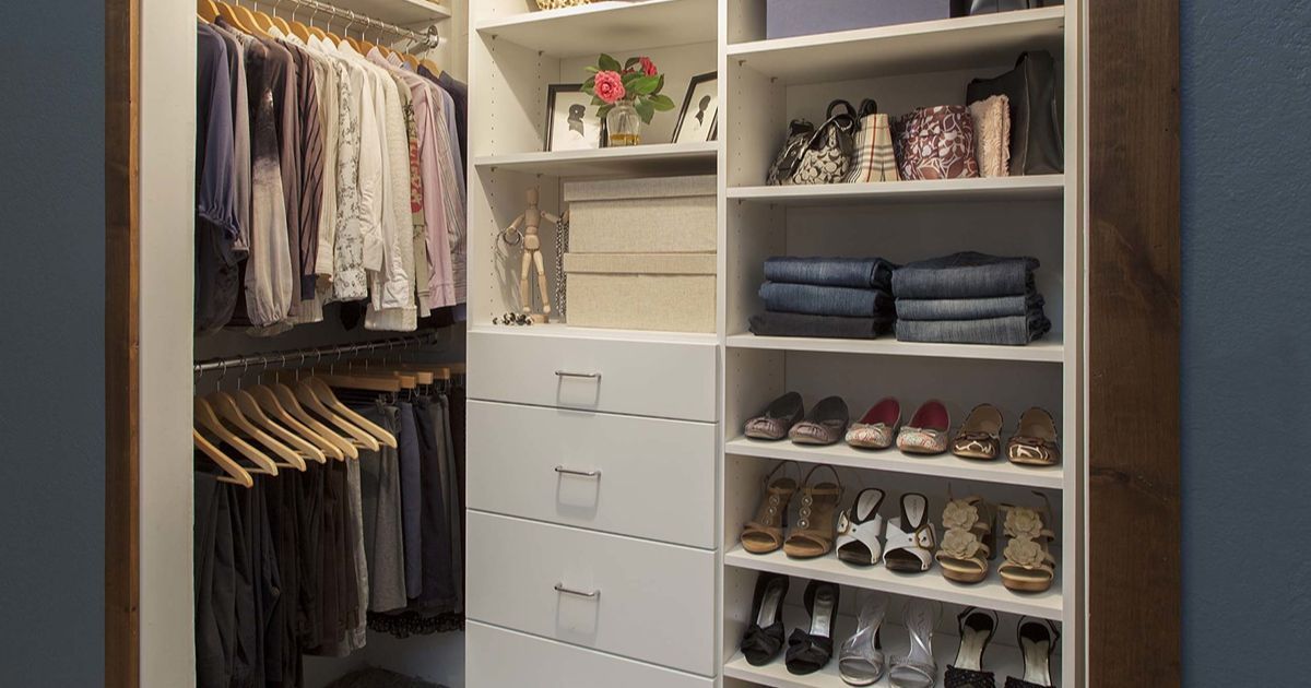 Walk-in closet with white shelving, clothes hanging, drawers, and shoes.