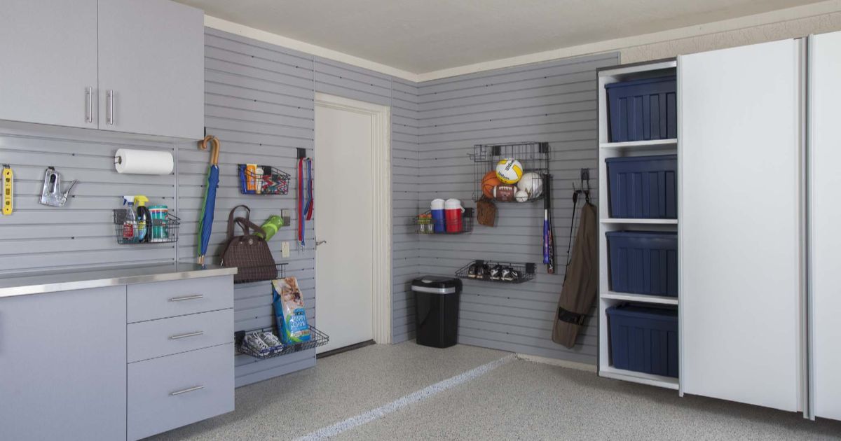 Organized garage with gray cabinets, wall storage, and a white door.