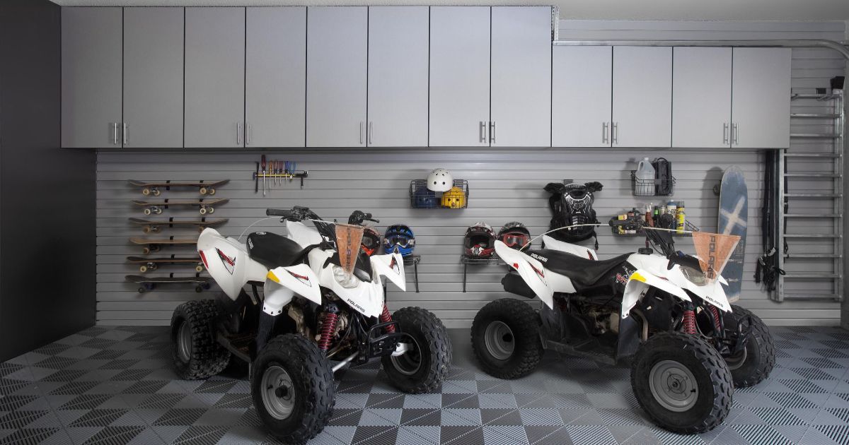 Two white ATVs parked in a garage with storage cabinets and wall organizers.