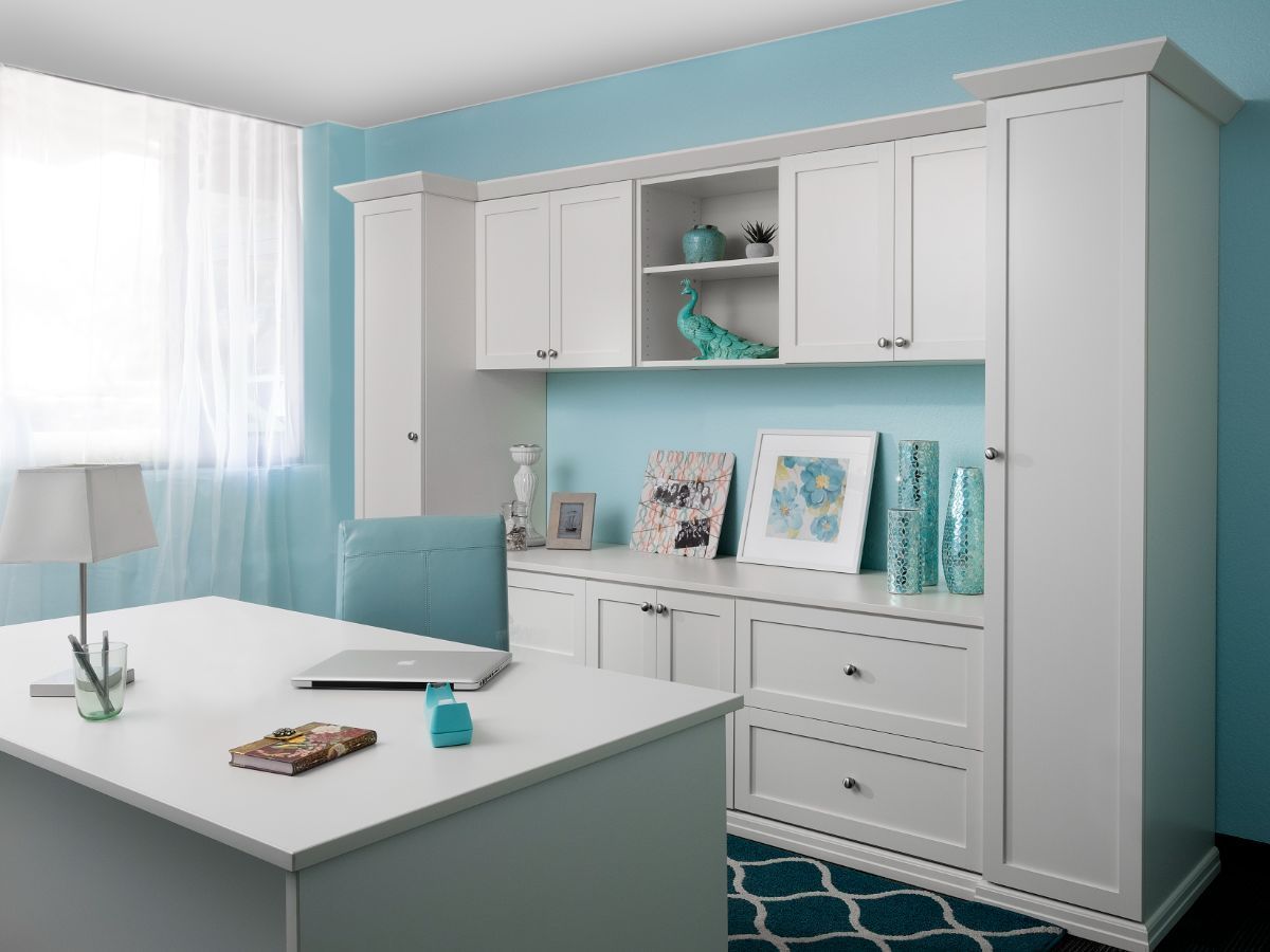 A white desk with a laptop on it in a room with blue walls