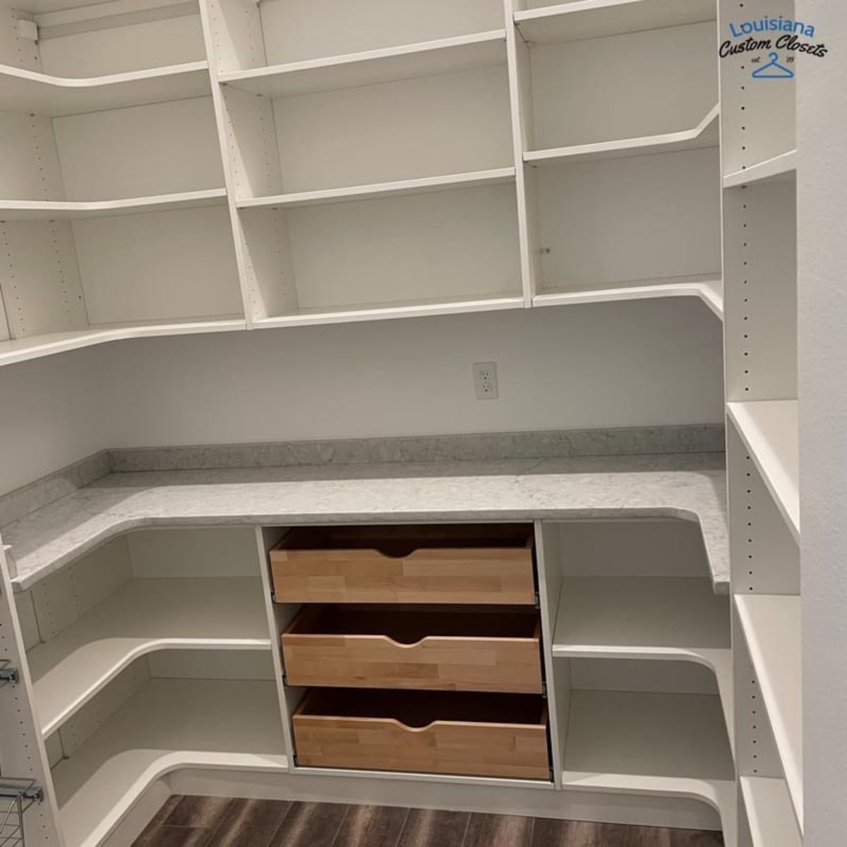 White pantry with built-in shelves and drawers. Features a countertop, and wooden-fronted drawers.