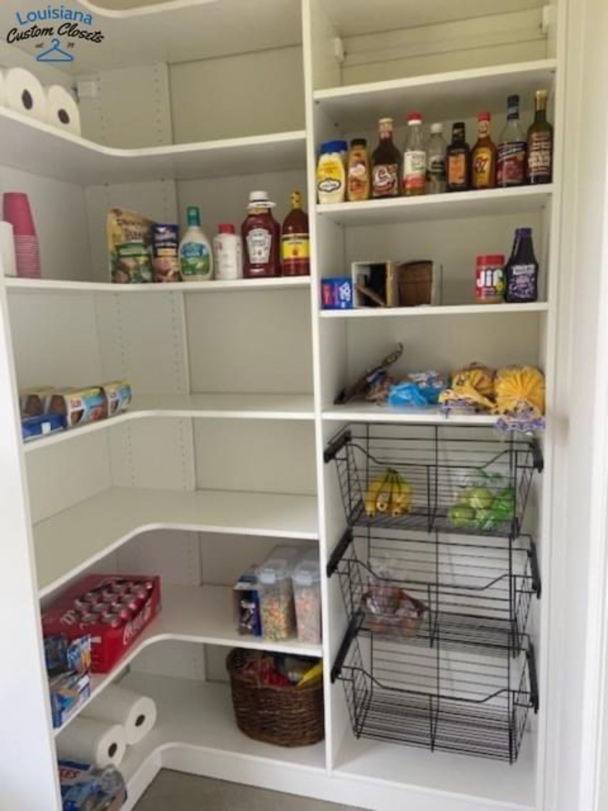 White pantry with shelves holding food items, baskets, and storage containers.