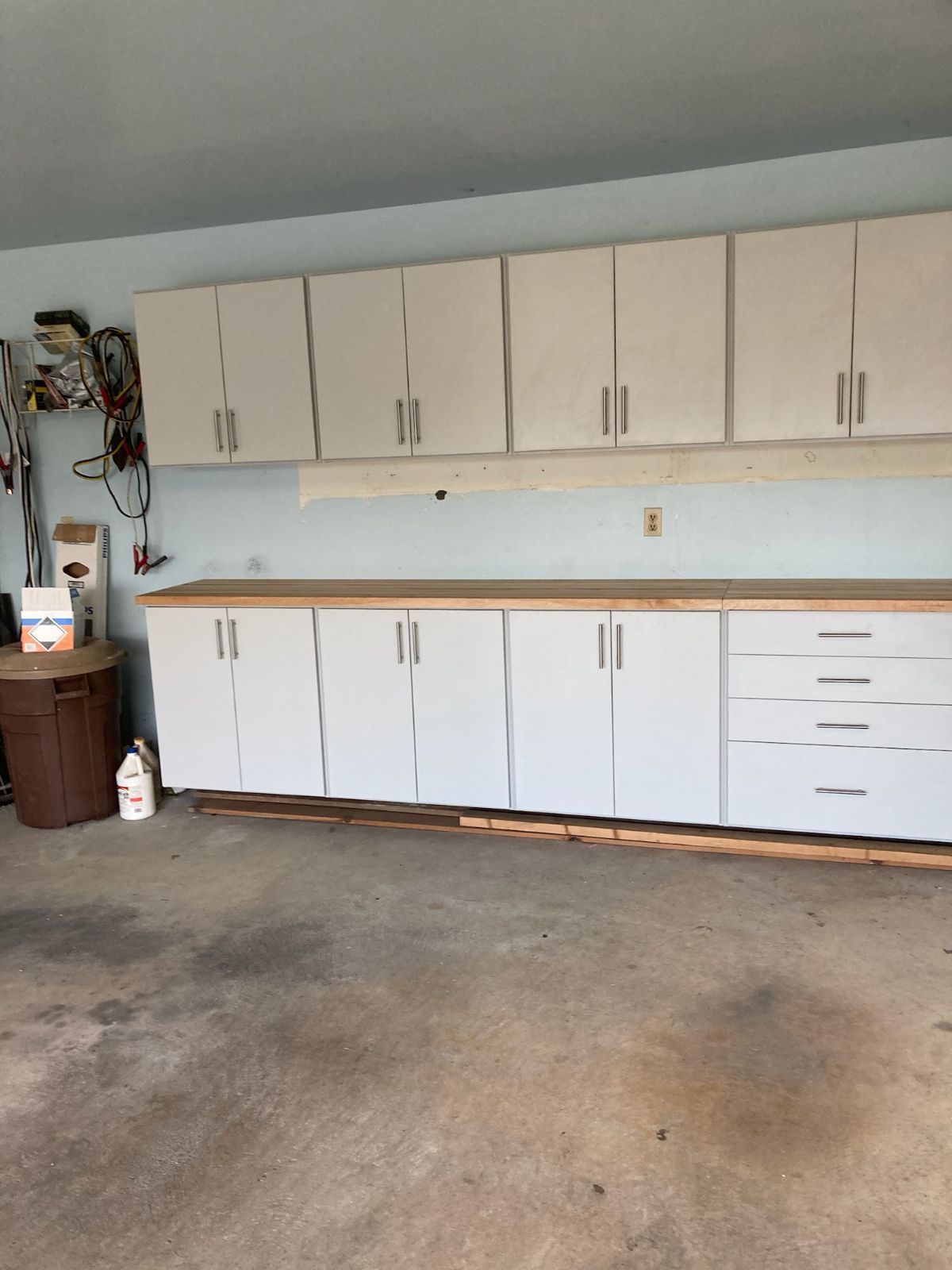 Garage with white cabinets, wooden countertop, and concrete floor.