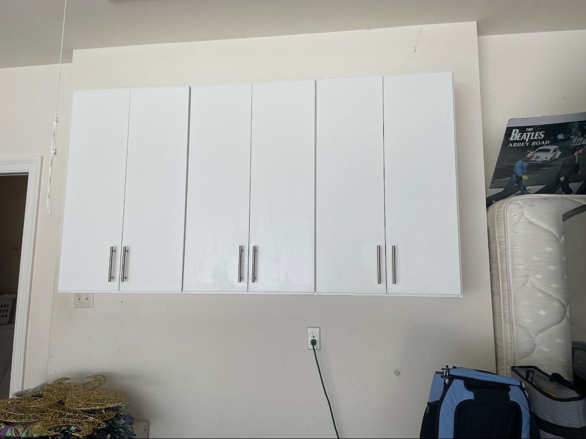 White cabinets mounted on a wall. Silver handles are on the closed cabinet doors.