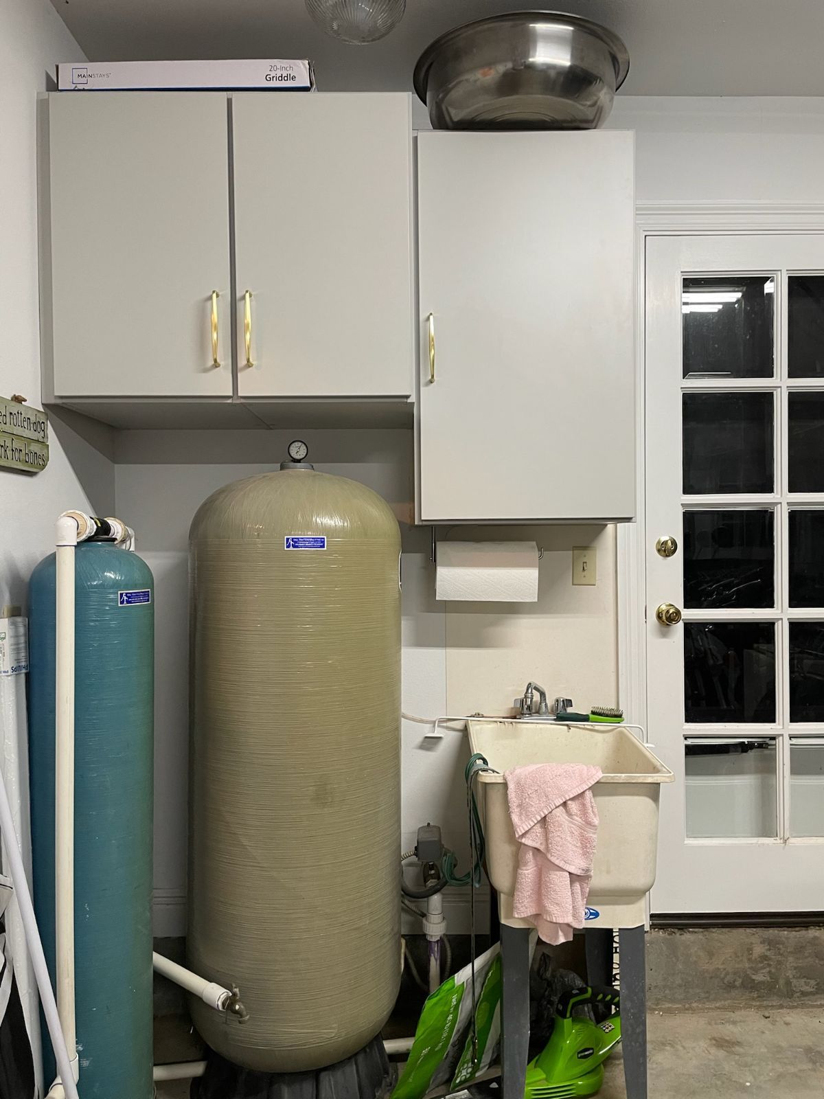 Garage corner with water tanks, cabinets, utility sink, and a door.