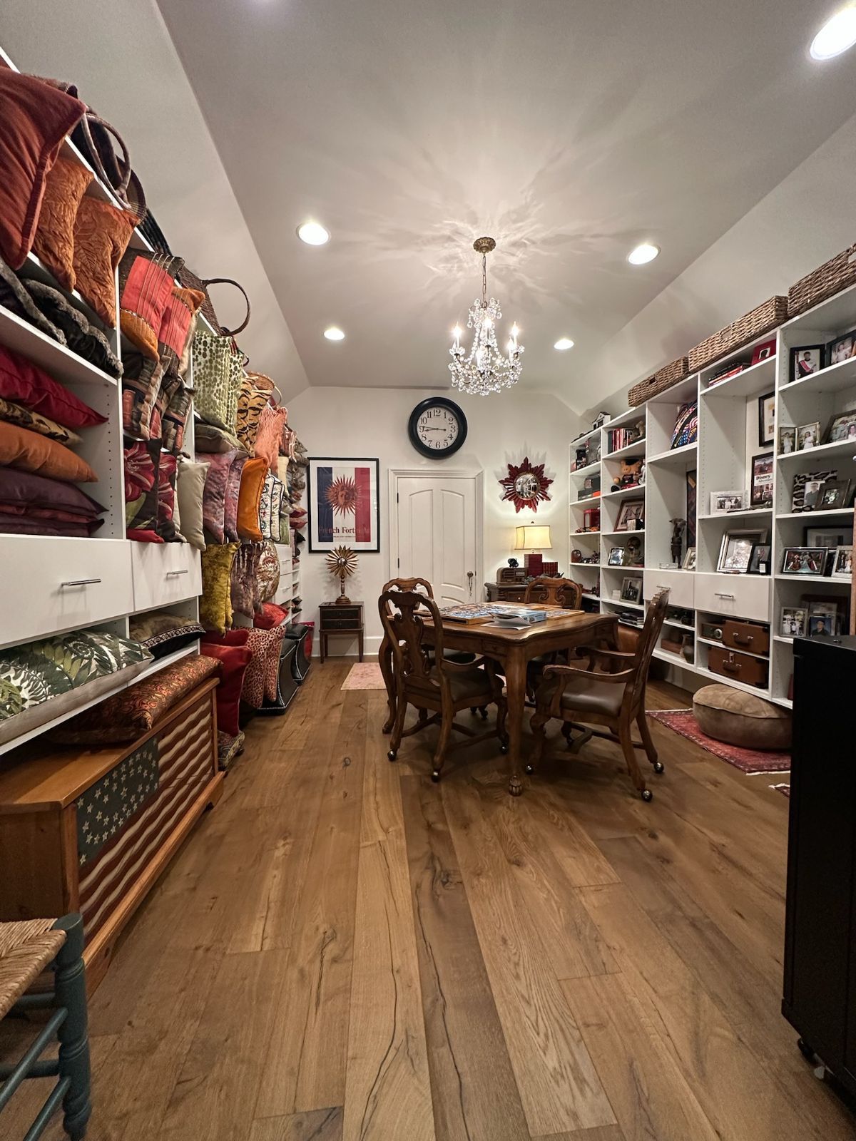 Room with built-in shelves on walls.  Wooden table and chairs centered. Decorative pillows and items on shelves.