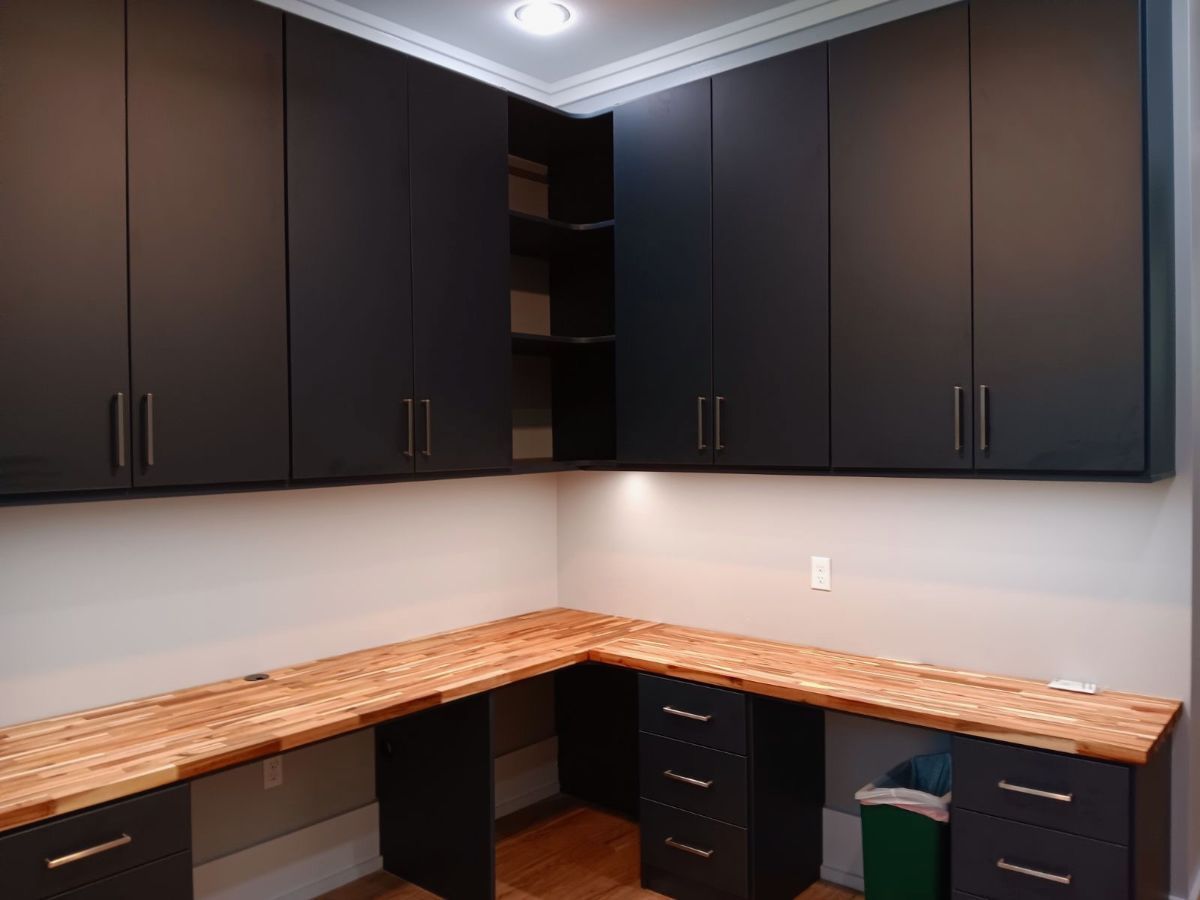 Dark cabinets over a wood corner desk in a room.