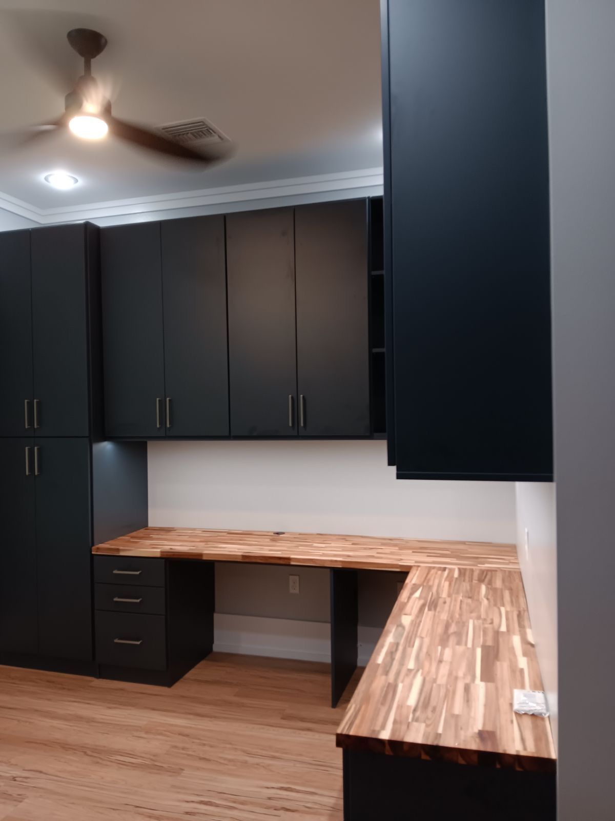 Dark gray home office with wood desk and cabinets.