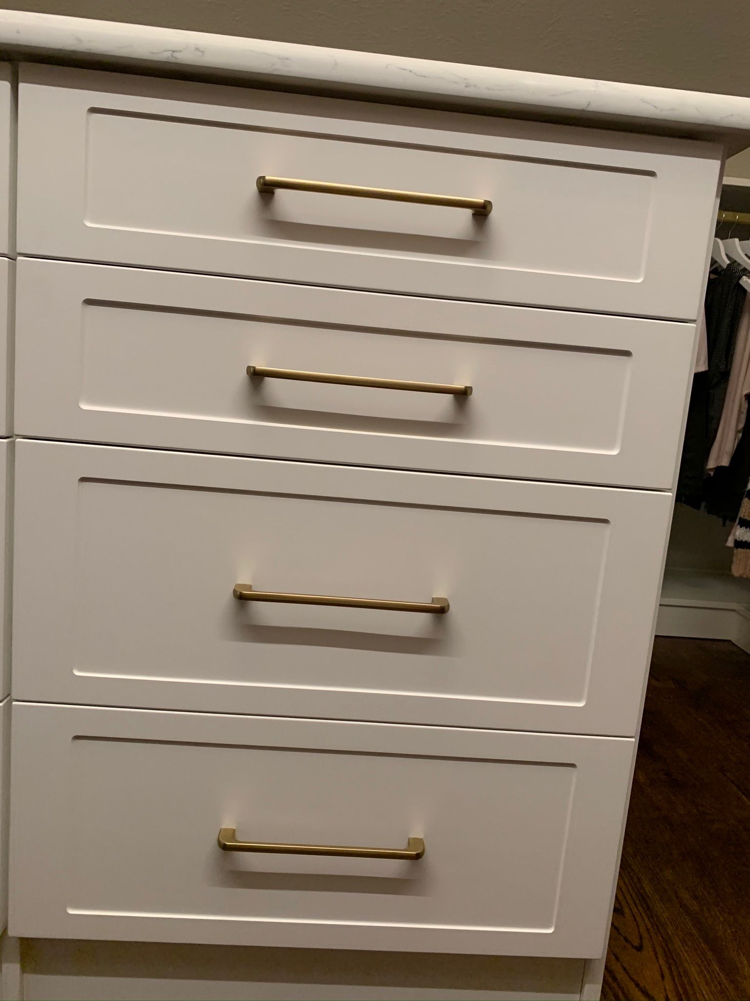 White drawers with gold handles in a built-in closet unit.