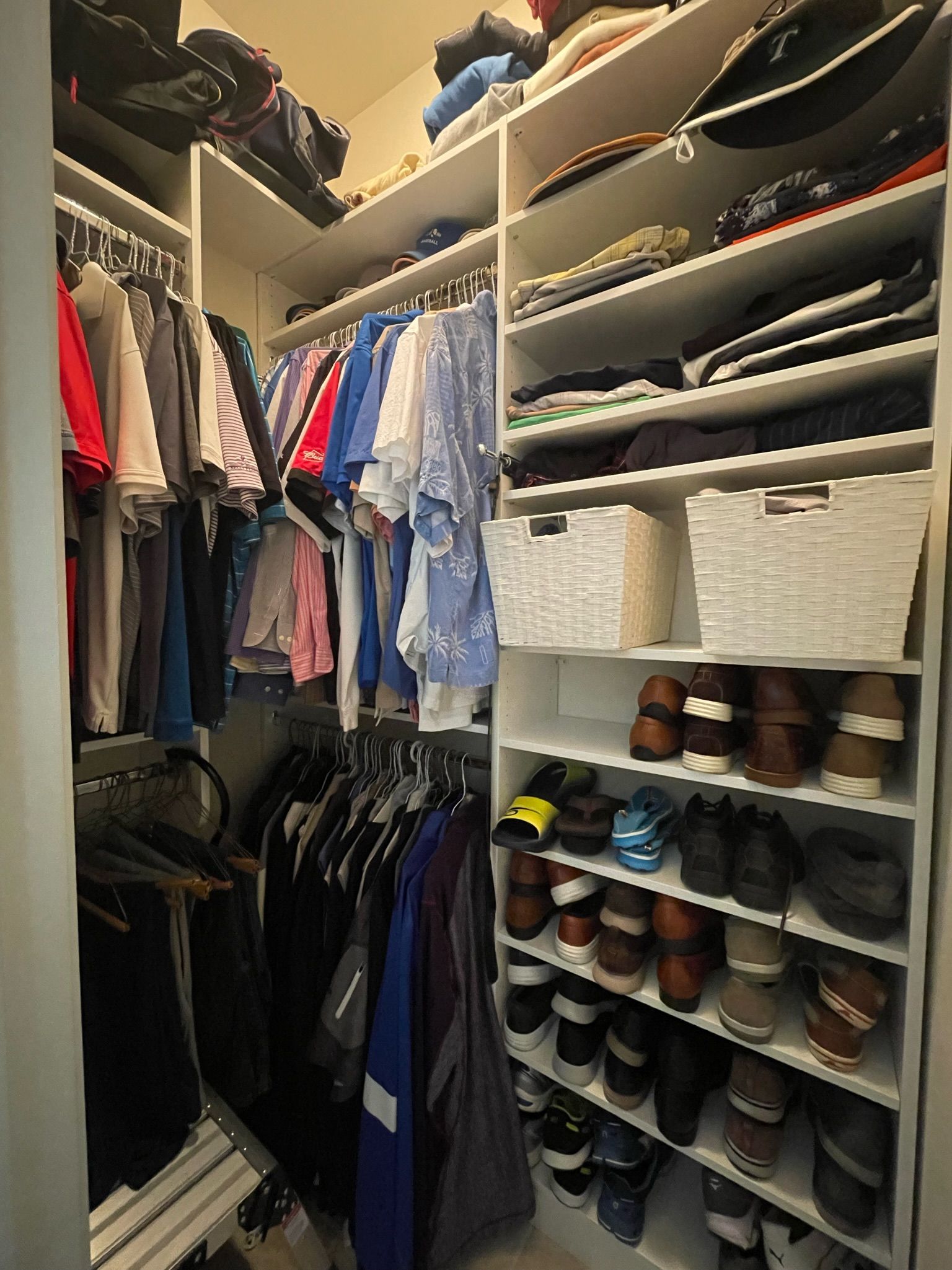 Walk-in closet with hanging clothes, shelves of folded items, and shoe storage. White shelves, various colored clothes.