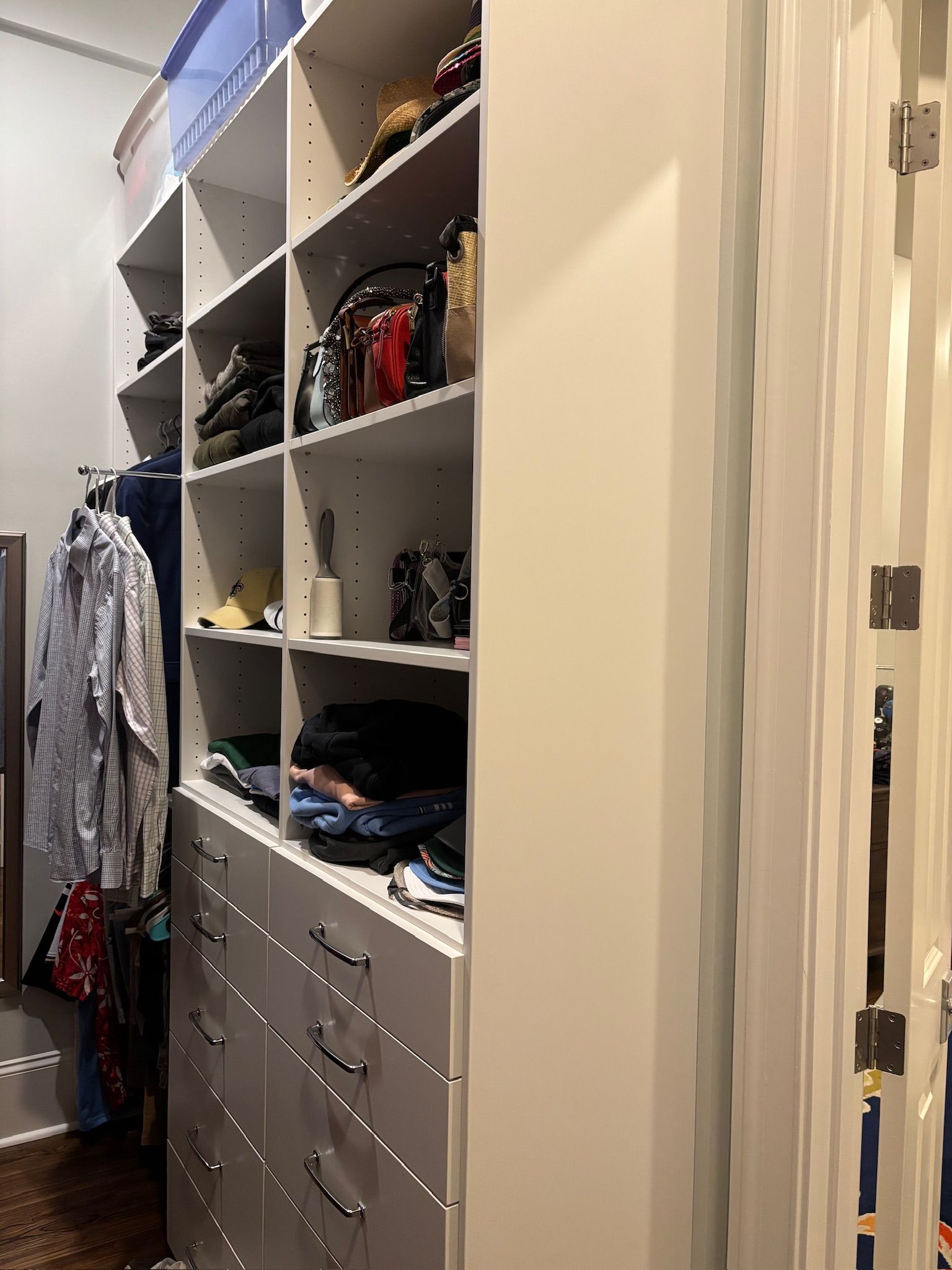 Built-in white closet with shelves, drawers, and hanging clothes.