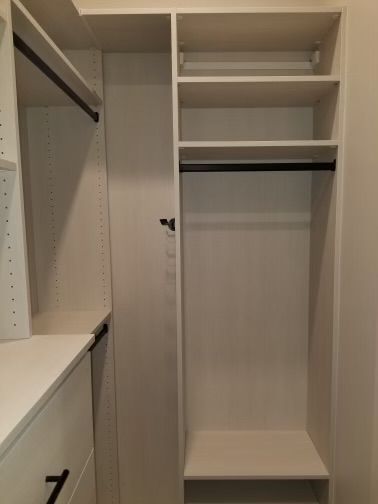 White closet with shelves, hanging rod, and drawers.