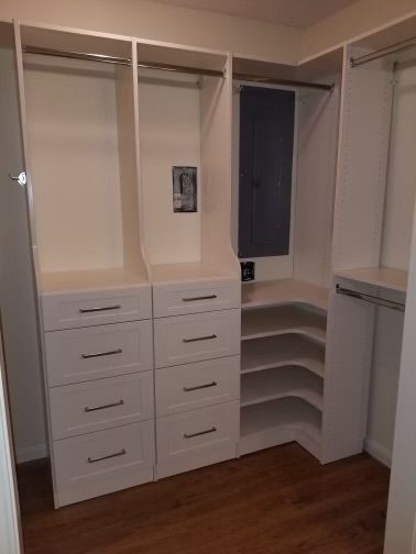 White walk-in closet with drawers, shelves, and hanging rods. The corner has curved shelves.