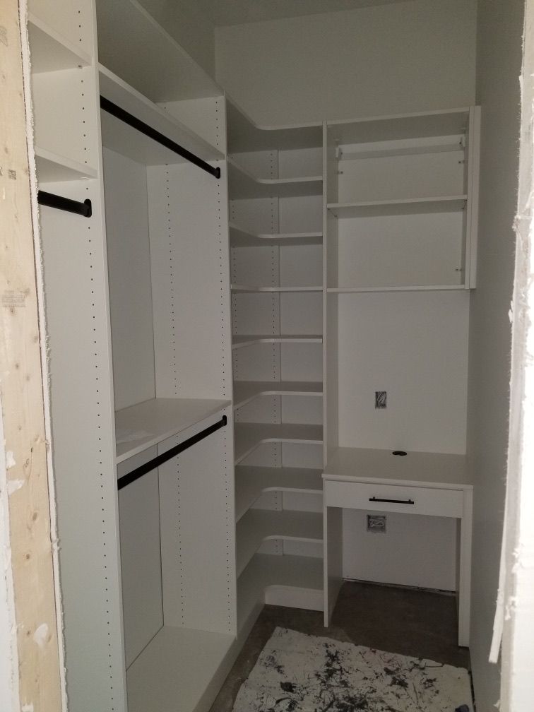 White closet with shelves, hanging rods, and a desk. Unfinished walls.