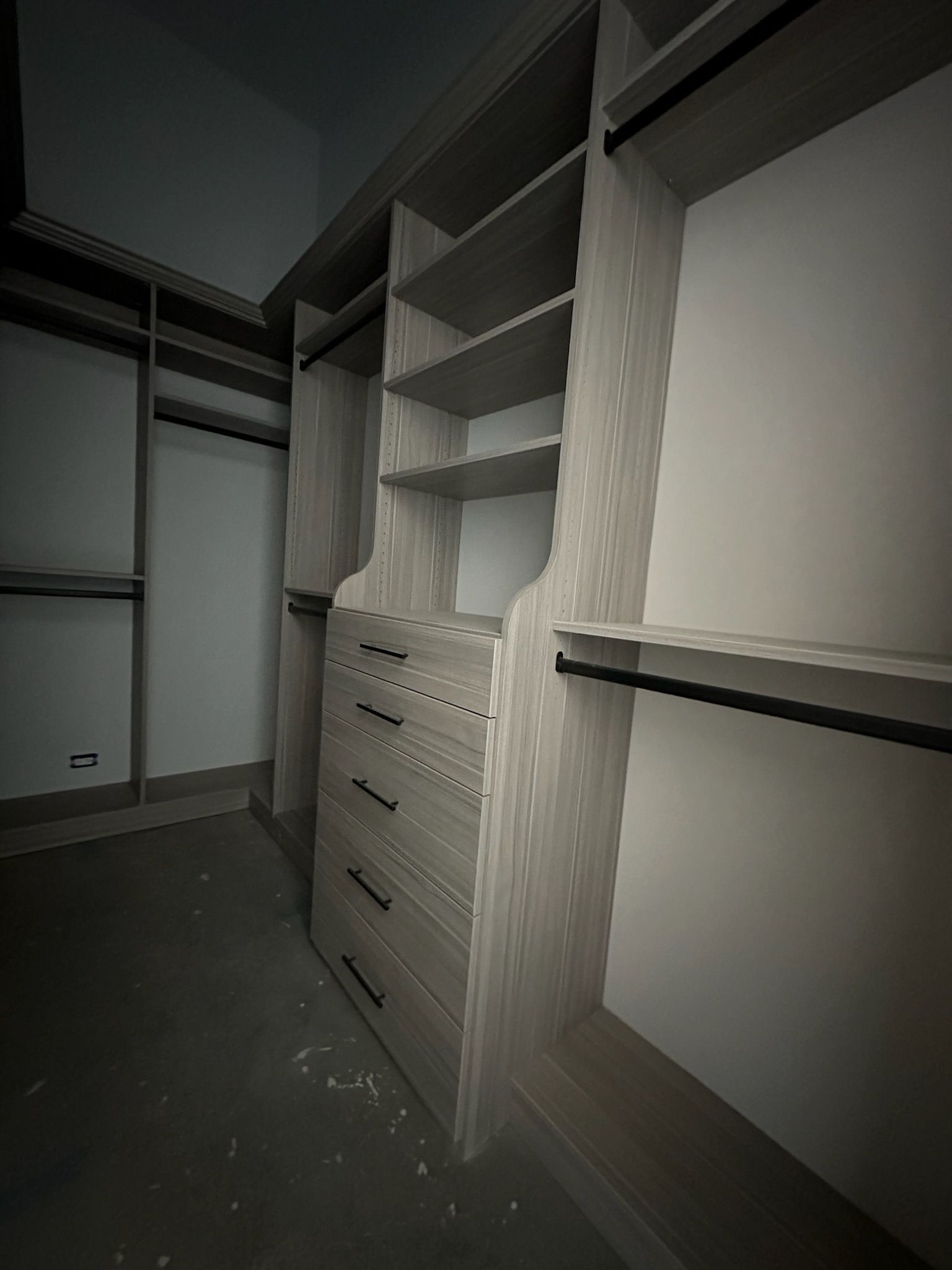 Built-in closet with shelves, drawers, and hanging rods. Light wood cabinetry against white walls.