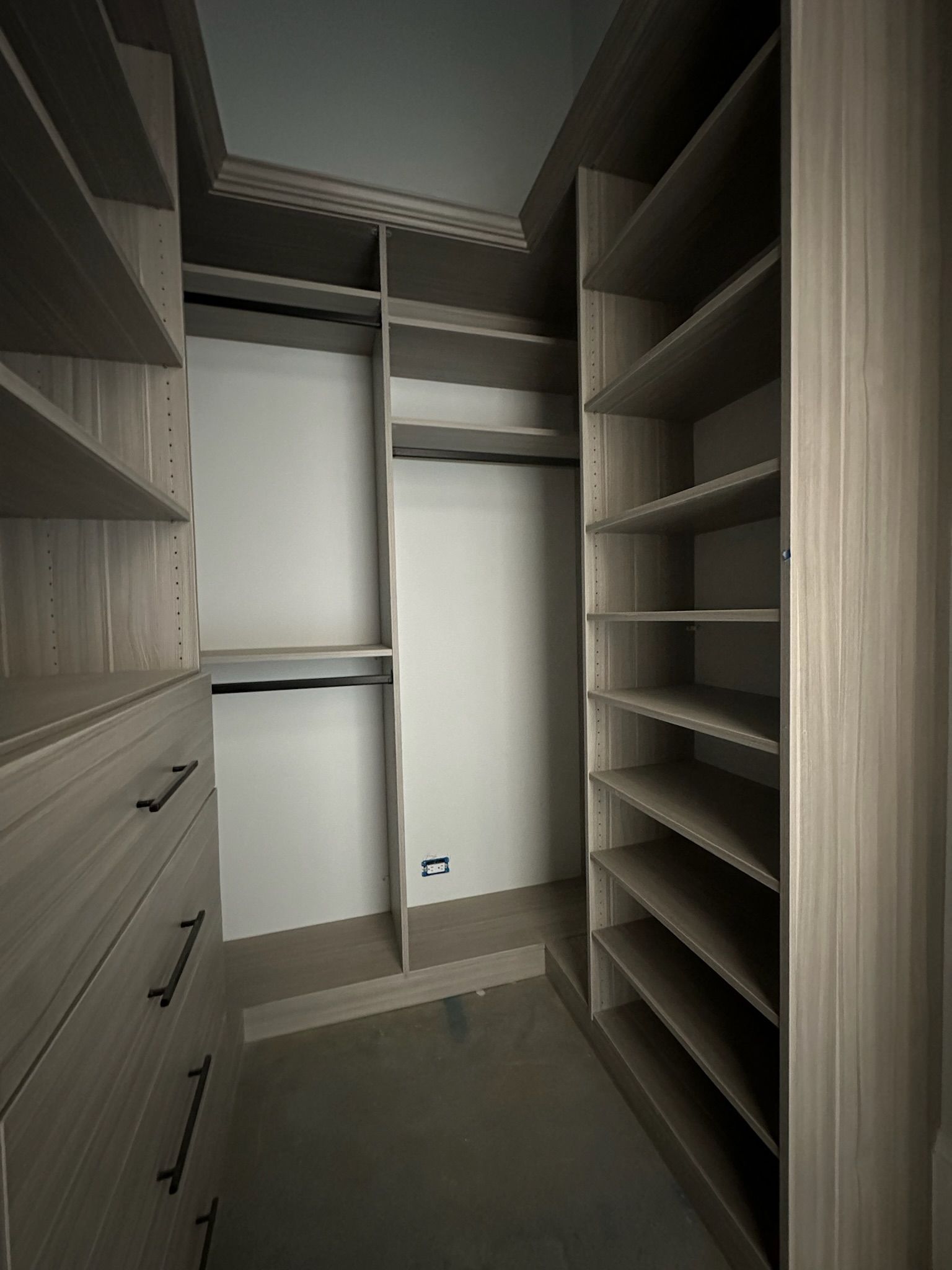 Walk-in closet with built-in shelves, drawers, and rods; neutral colors and organized storage.
