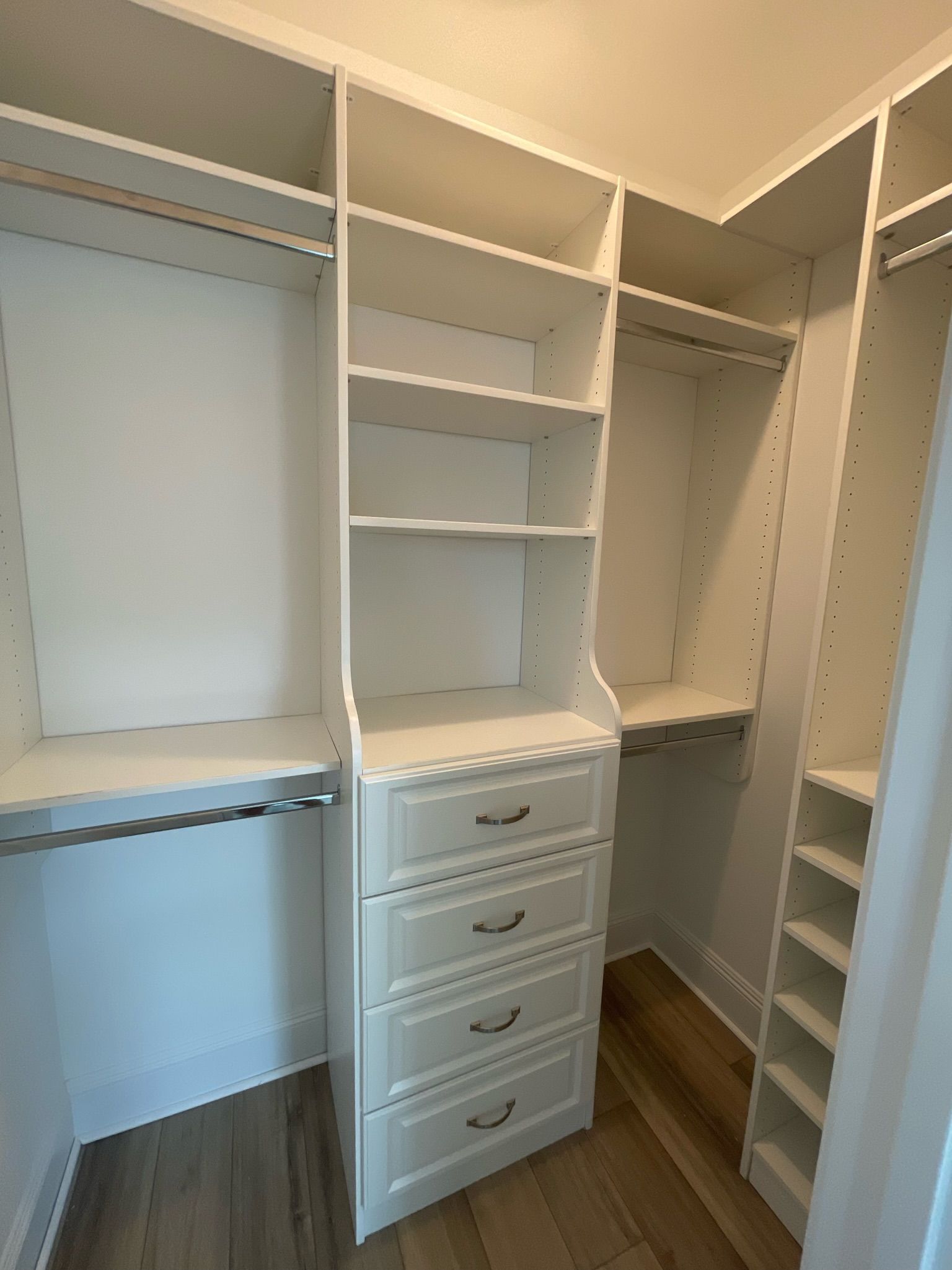 White custom closet with shelves, drawers, and hanging rods.