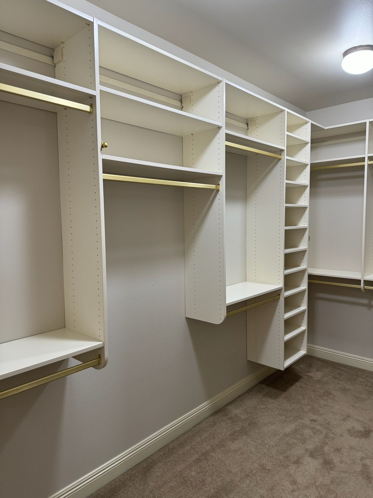Walk-in closet with white shelving, metal rods, and beige carpet.