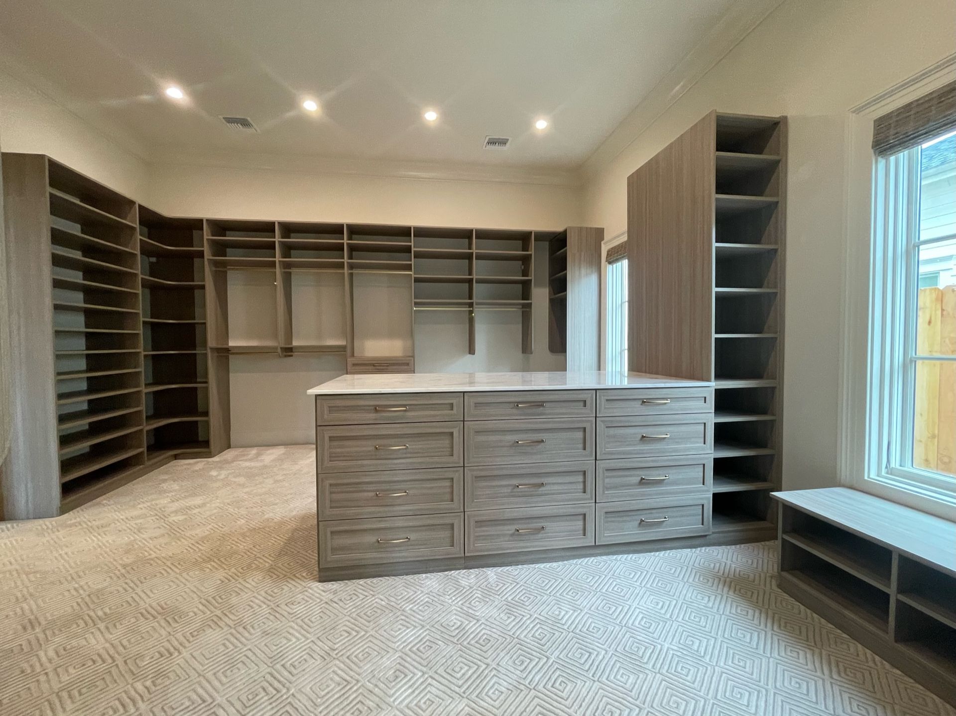 Walk-in closet with gray cabinetry, a central island with drawers, and built-in shelving.