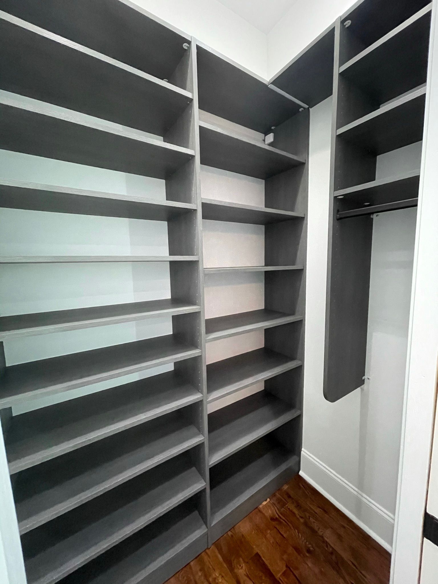 Gray closet shelving with various shelves and a hanging rod.