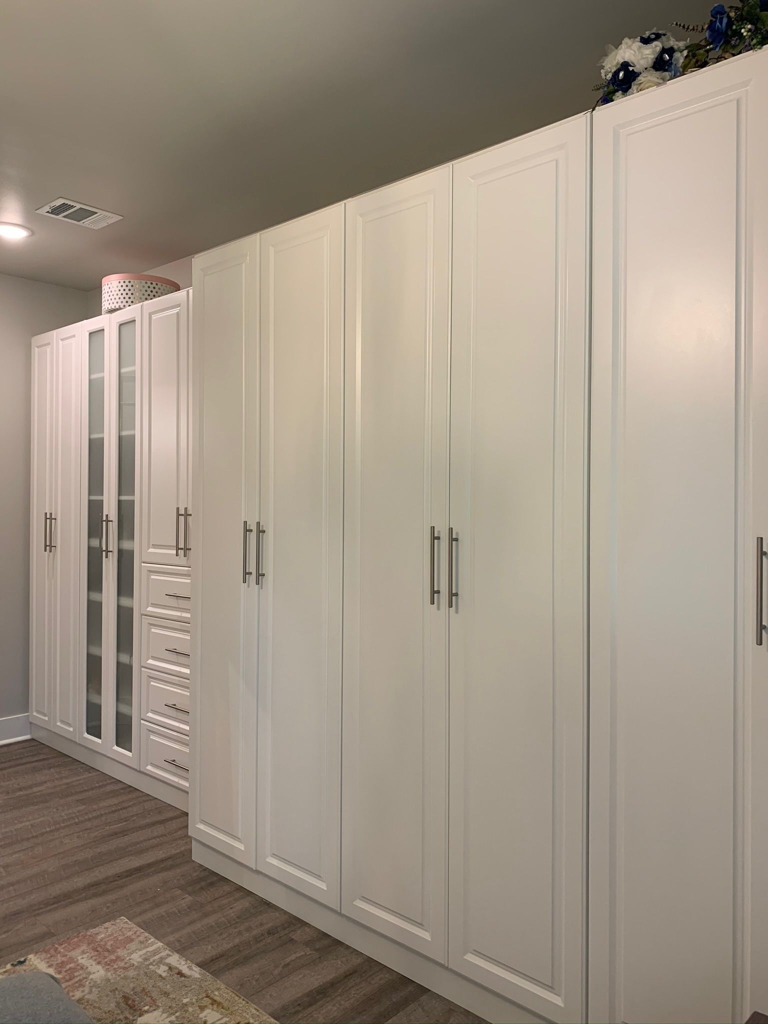 White closet with several tall doors and a glass door section in a room with a rug.