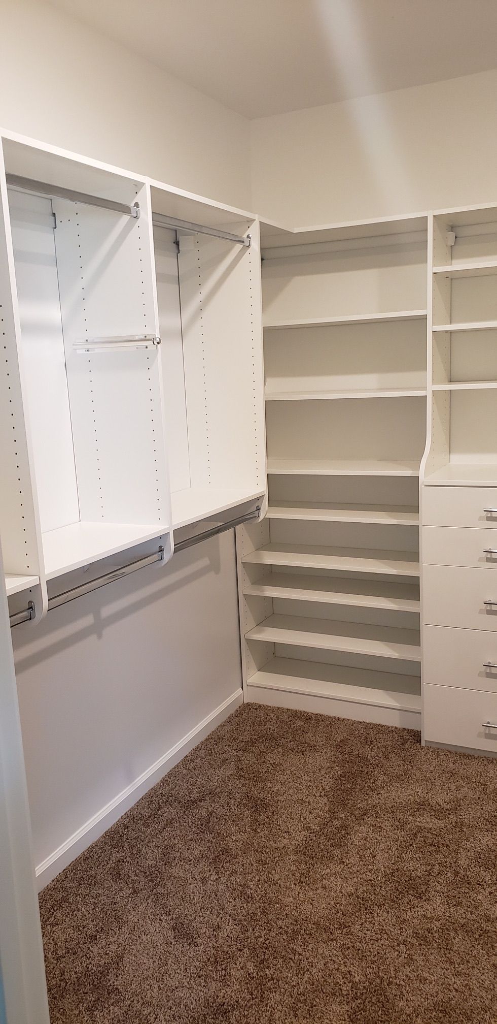 Empty white closet with carpeted floor and shelving.
