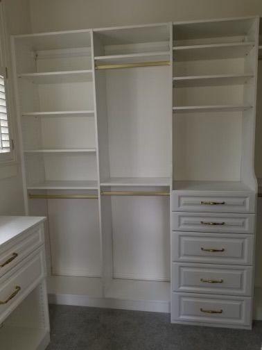 White closet organizer with shelves, drawers, and hanging rods.