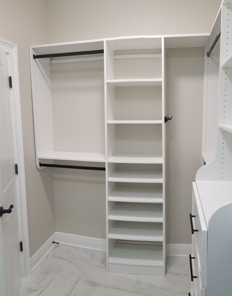 White custom closet with shelves and hanging rods, built-in against a light gray wall.