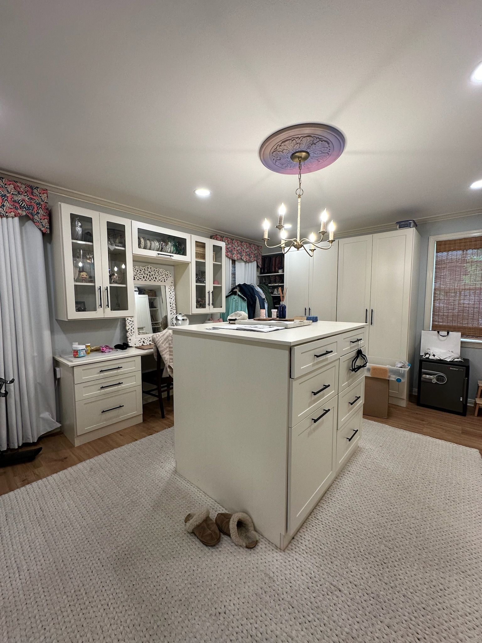 Kitchen with white cabinetry and island, ornate ceiling light, and large fluffy rug.