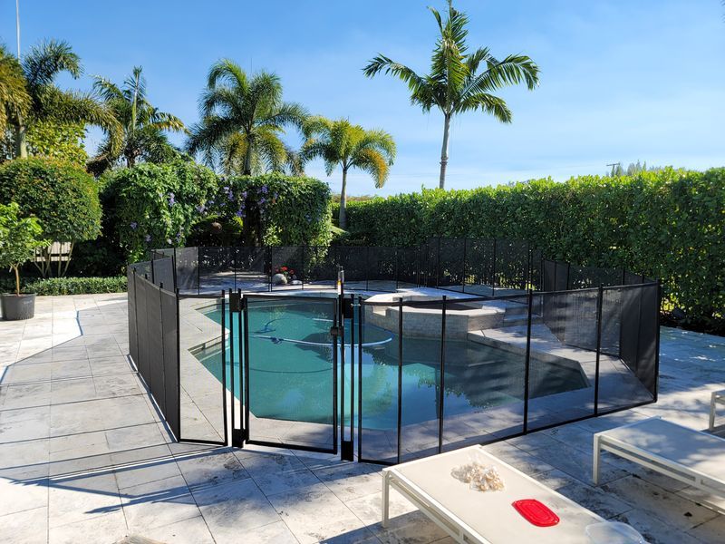 A swimming pool with a fence around it and palm trees in the background