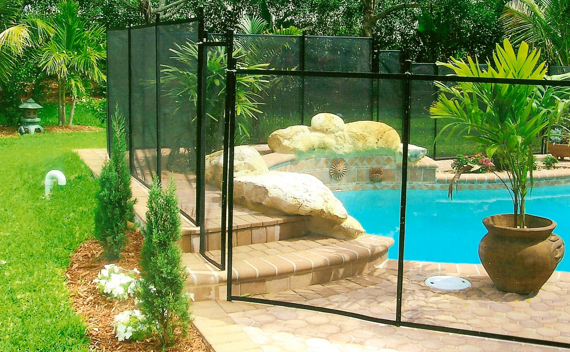 A fence surrounds a swimming pool in a backyard