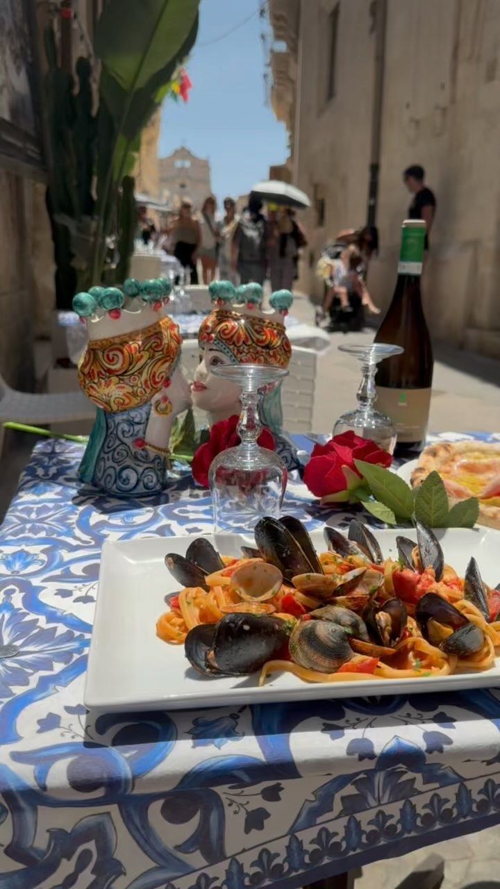 Un tavolo sormontato da piatti di cibo e una bottiglia di vino.