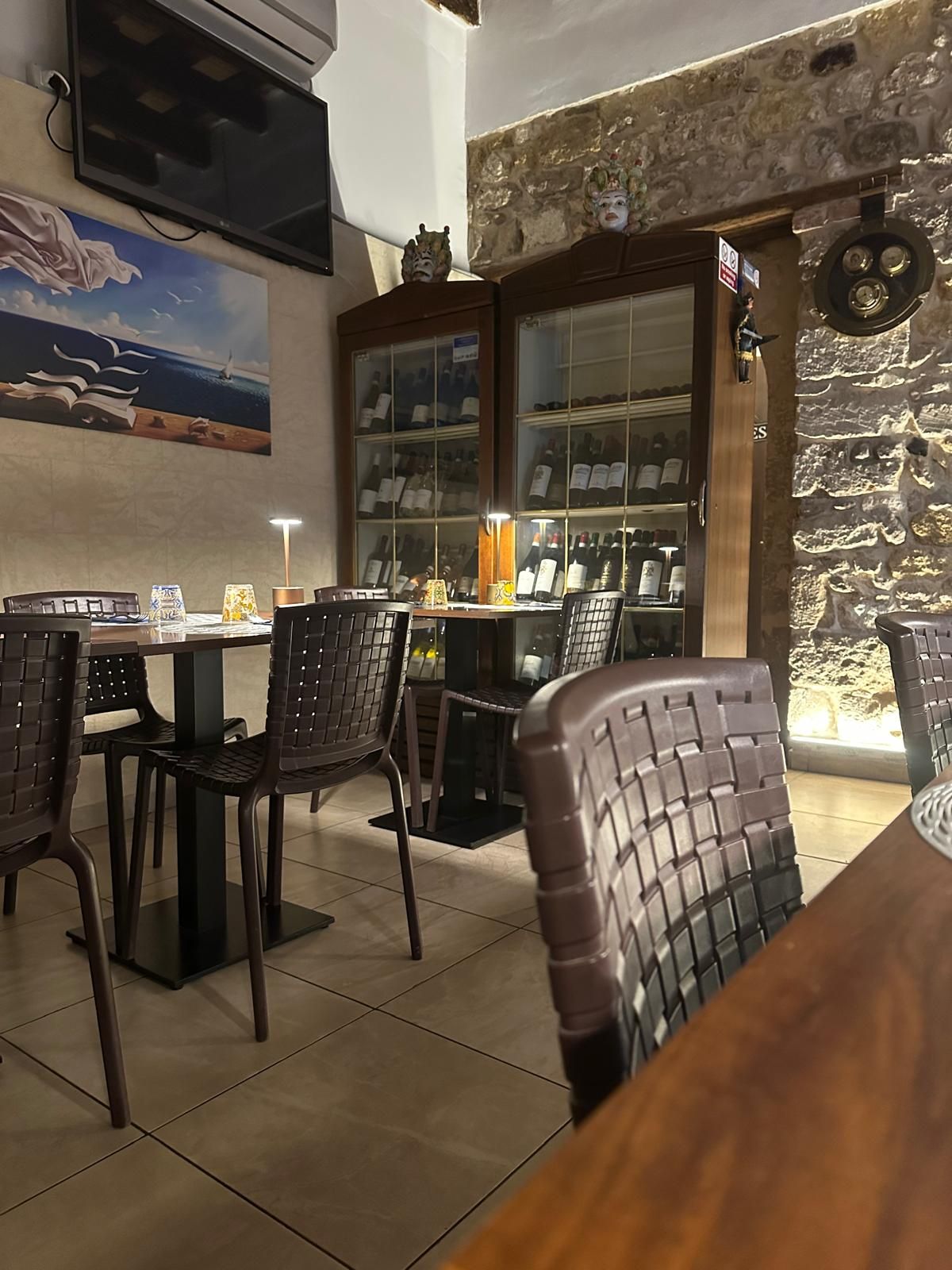 Un ristorante siciliano a Ortigia con tavoli e sedie e una tv a parete