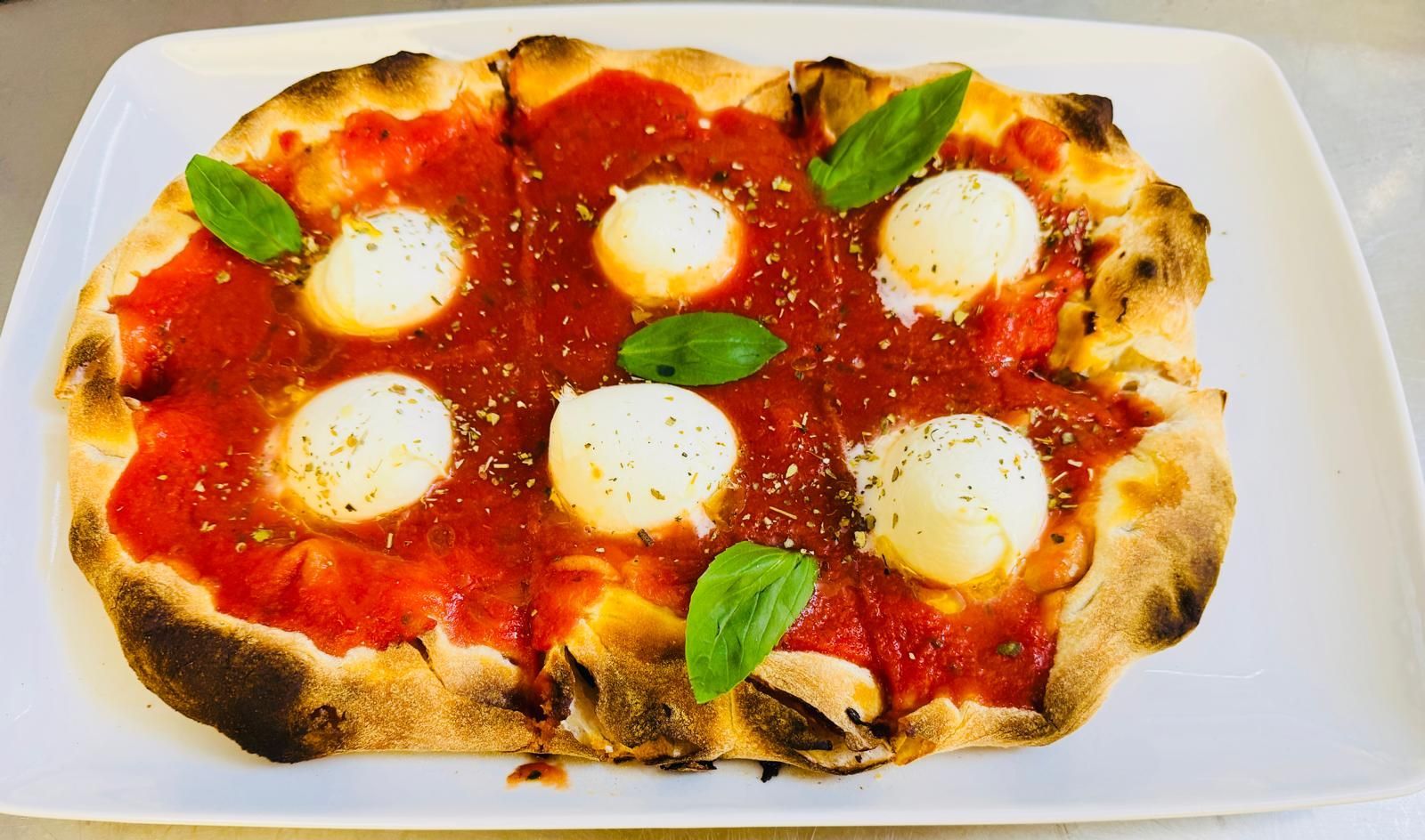 Una pizza con salsa di pomodoro e formaggio su un piatto bianco.