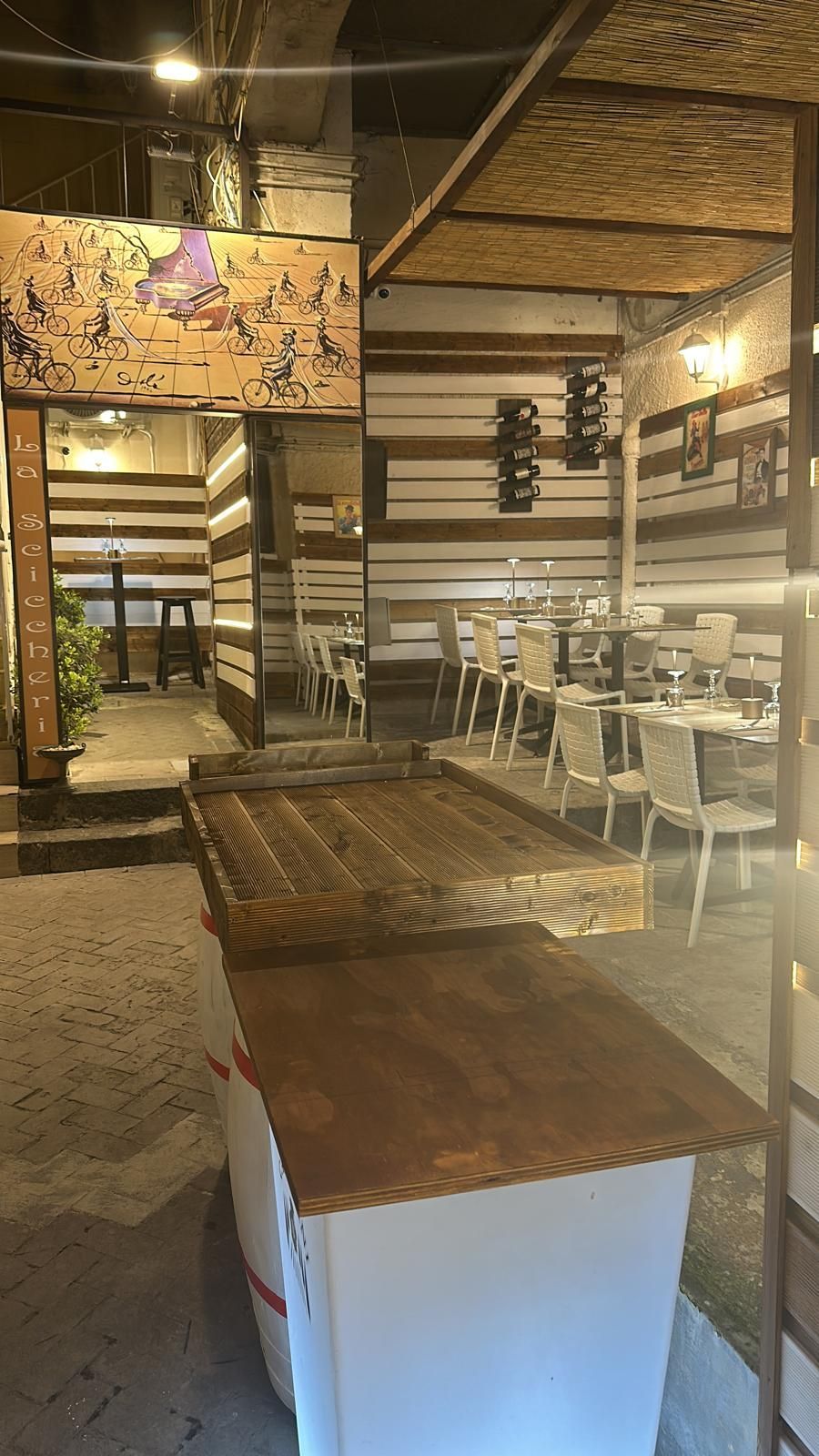 Un ristorante tipico a Siracusa con tavoli e sedie e un tavolo di legno al centro della stanza.