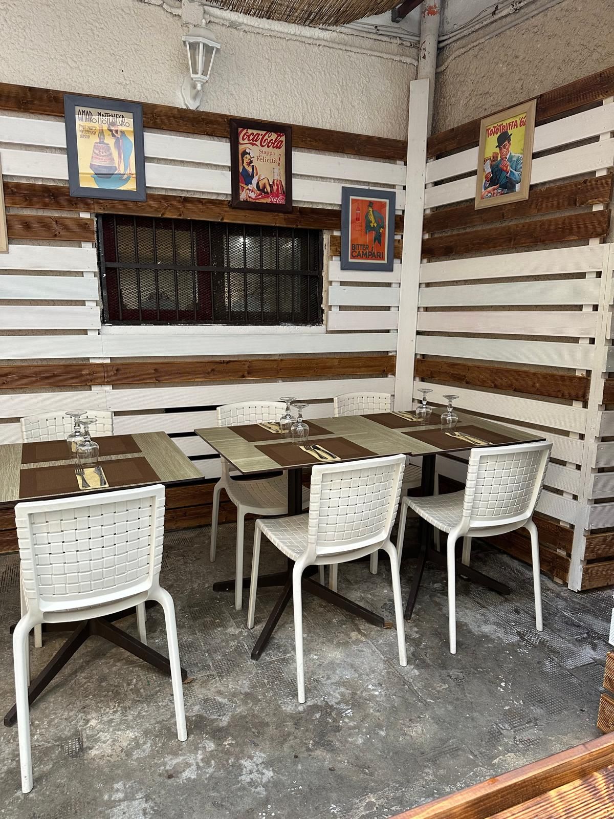 Un ristorante siciliano a Siracusa con tavoli, sedie e una parete di legno del ristorante siciliano a Siracusa.