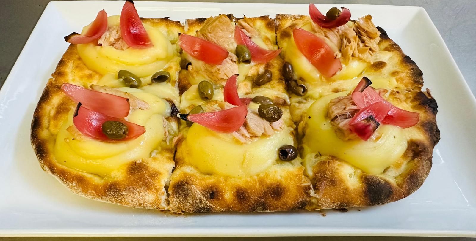 Una pizza con pomodori e olive su un piatto bianco.