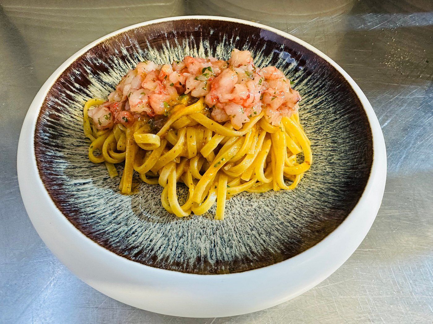 Su un tavolo c'è una ciotola di noodles con gamberi sopra.