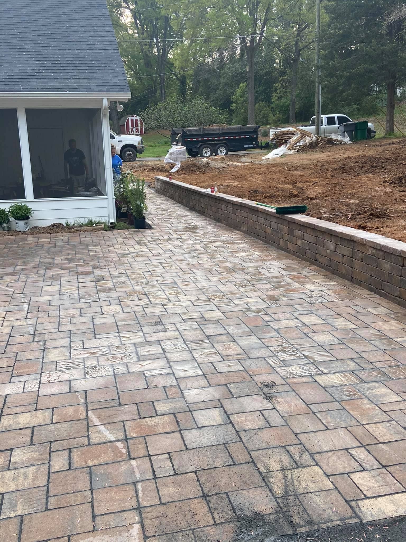 A brick driveway leading to a house with a screened in porch.