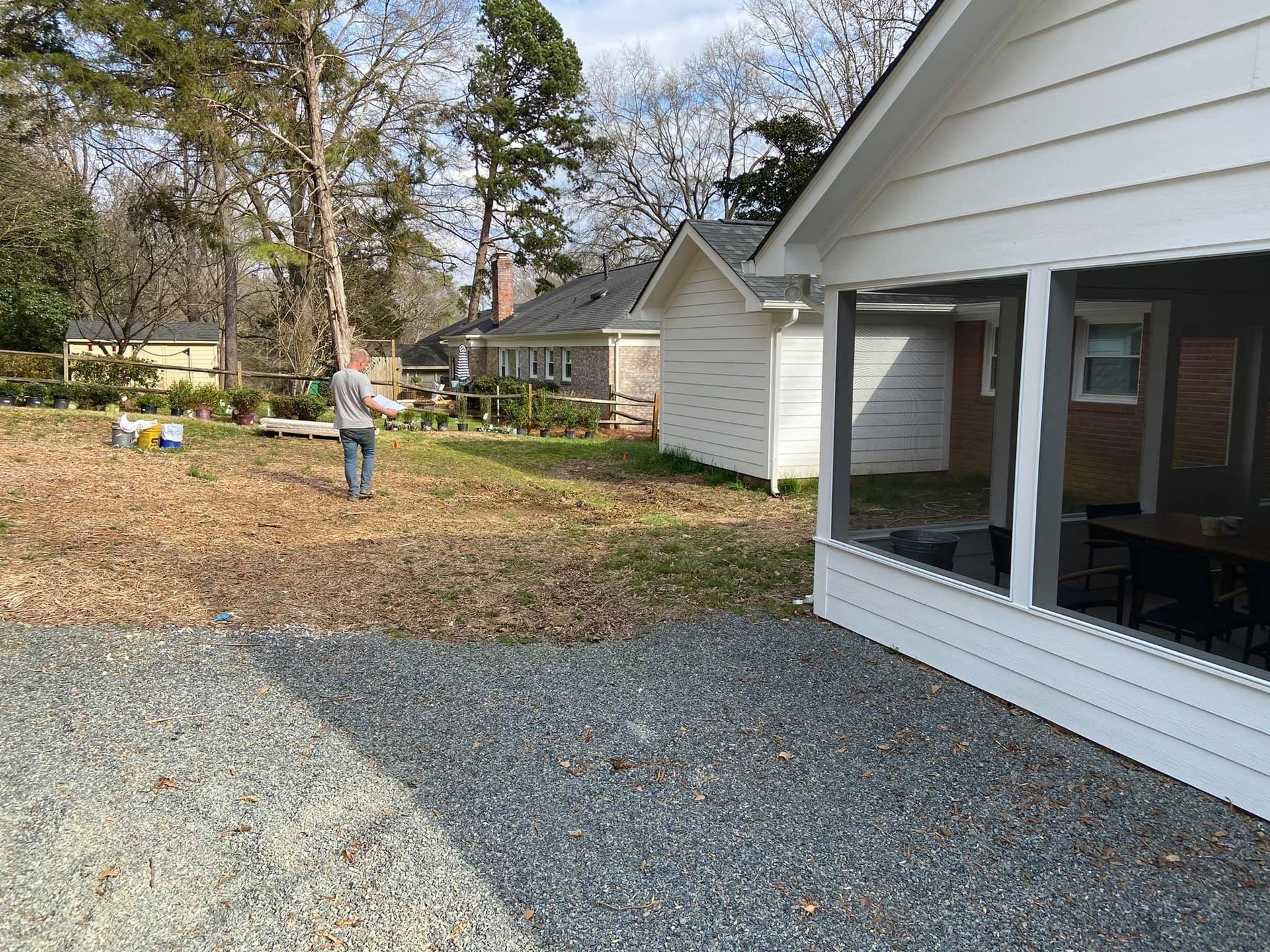 A man is standing in front of a house with a screened in porch.