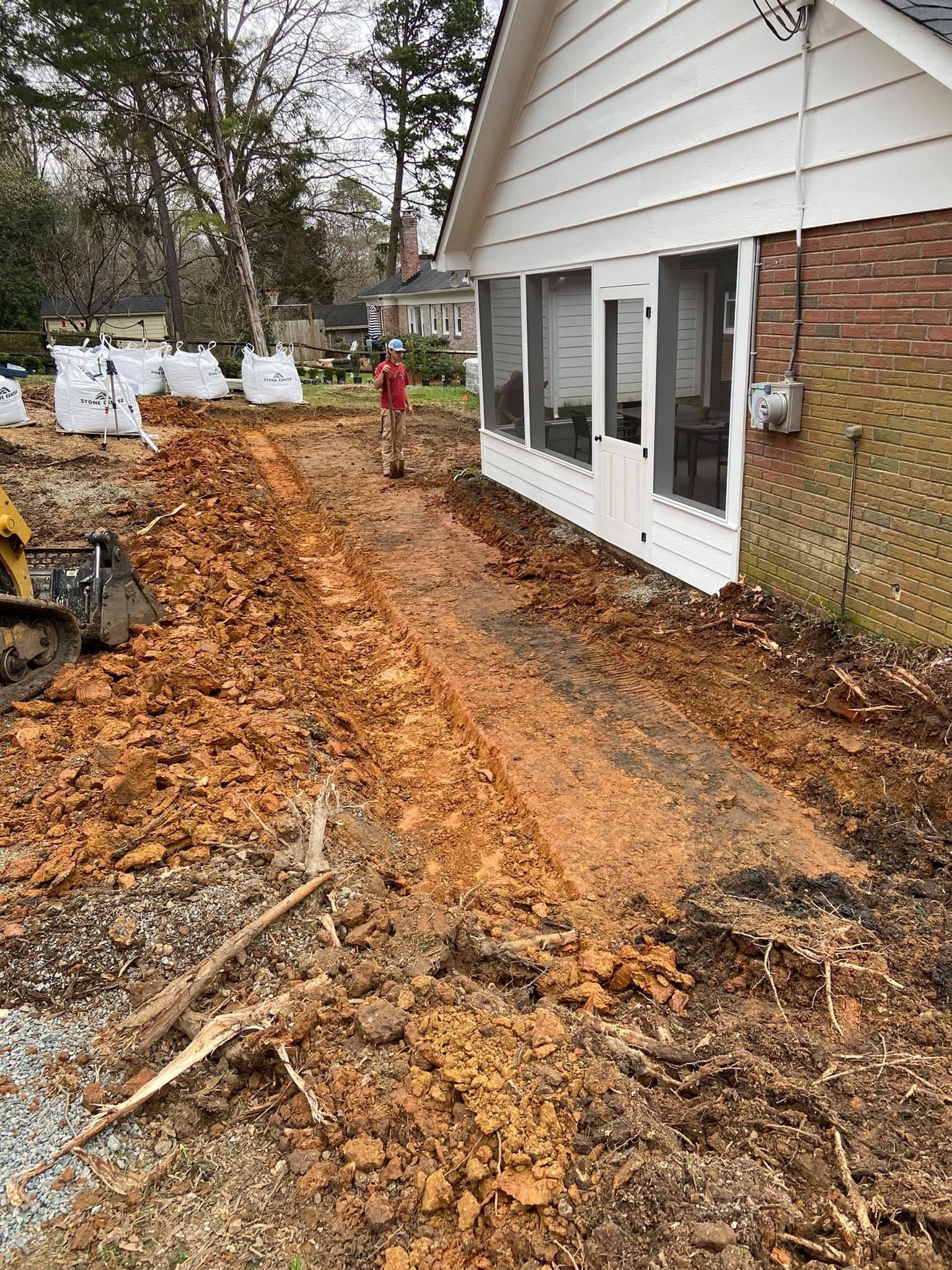 A man is standing in the dirt in front of a house.