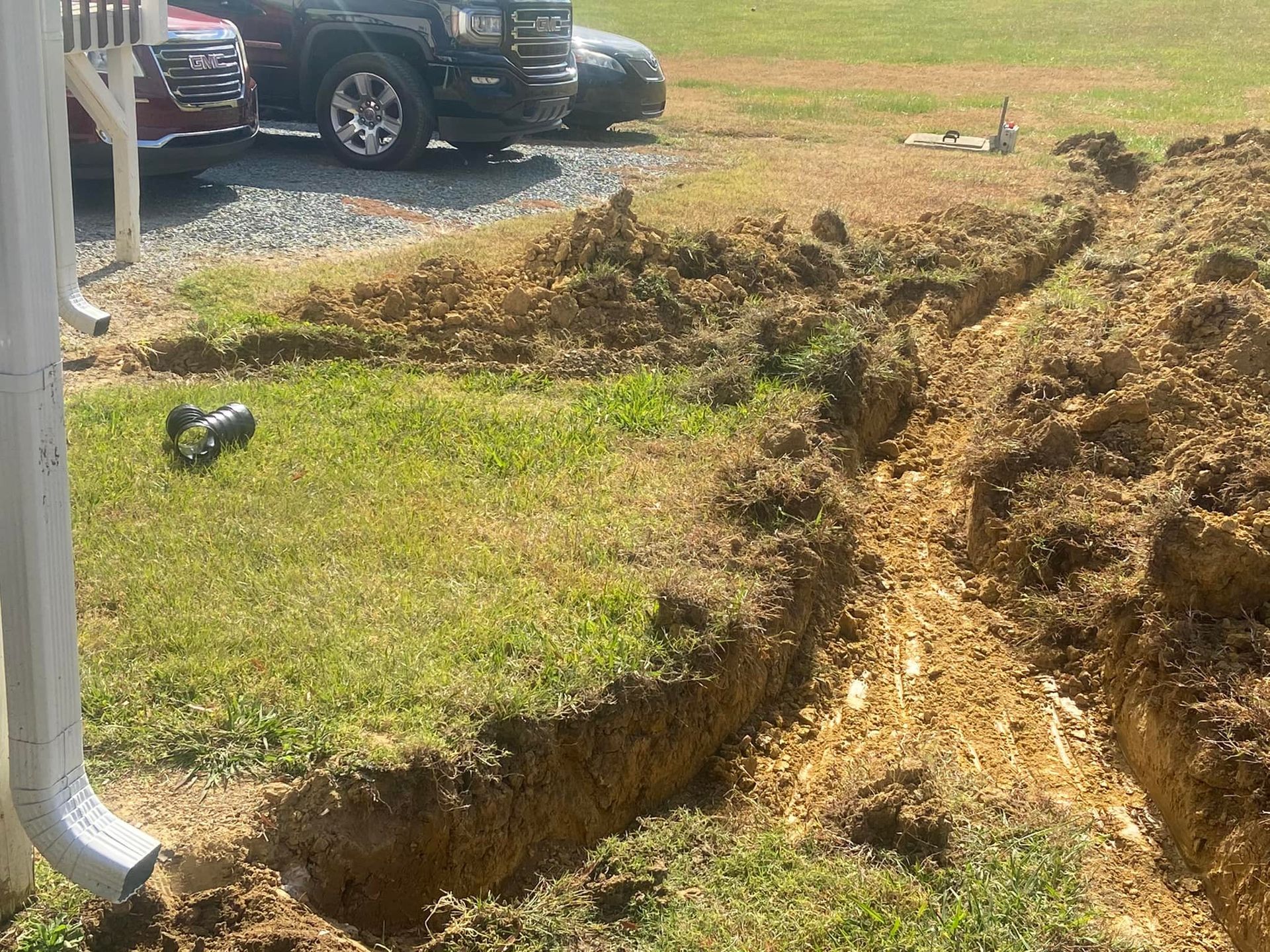 A jeep is parked in a driveway next to a pile of dirt.