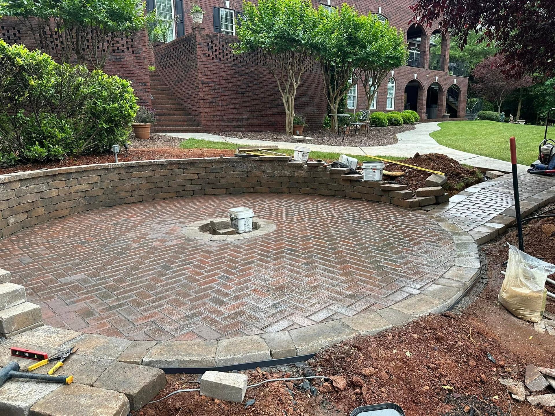 A brick patio is being built in front of a house.