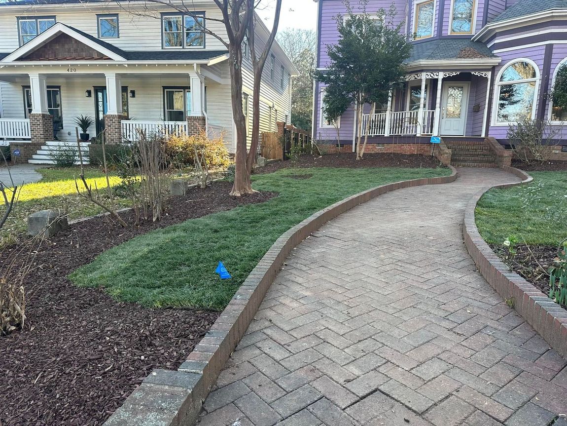 A brick walkway leading to a purple house and a white house.